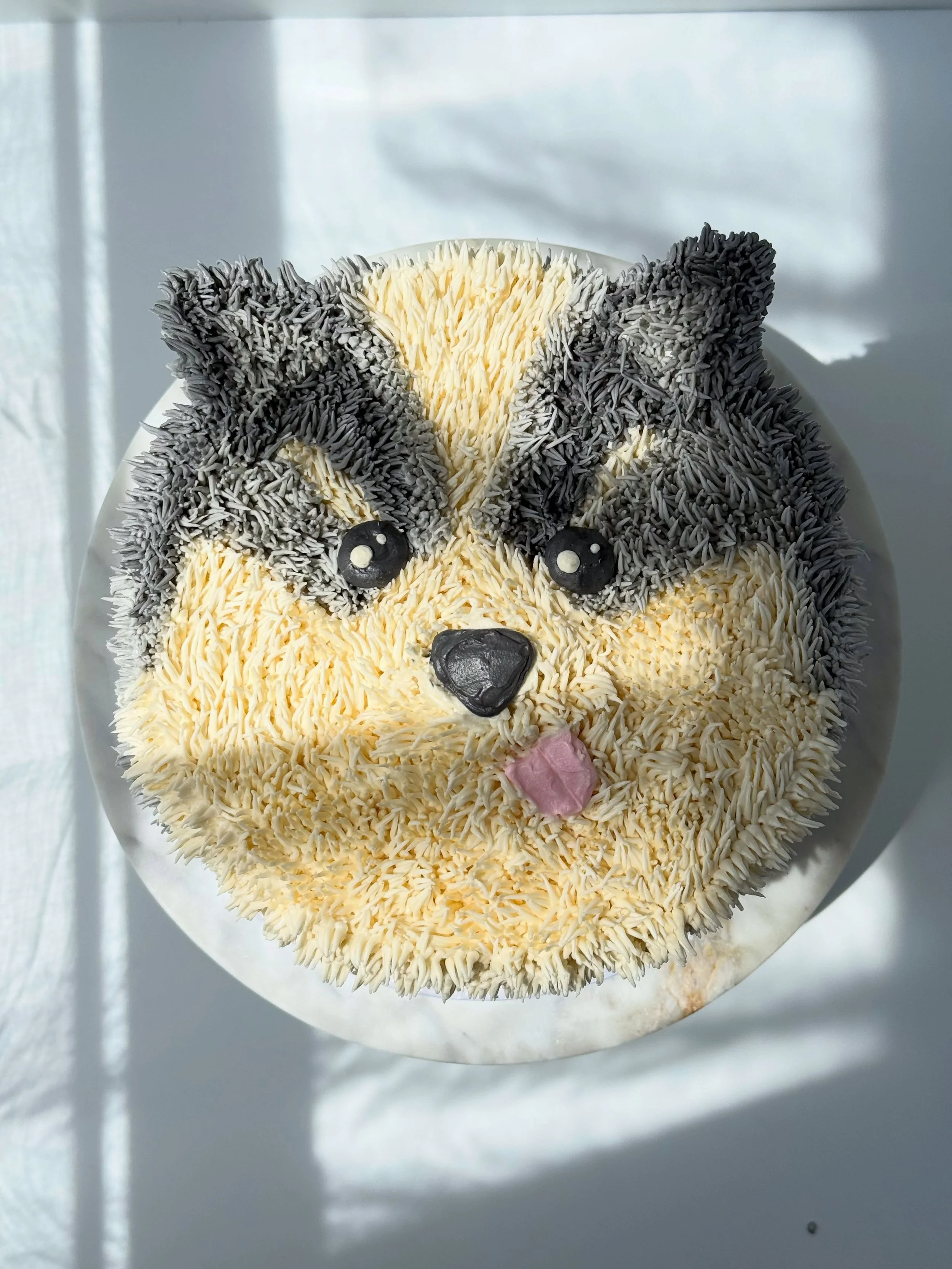 Husky cake 

✨if you scroll to the last image you can see how I began 

✨I wanted the nose area to be raised and used a toothpick to draw out the different colored areas

✨then I went to town with my grass piping tip in two shades of gray and white 
