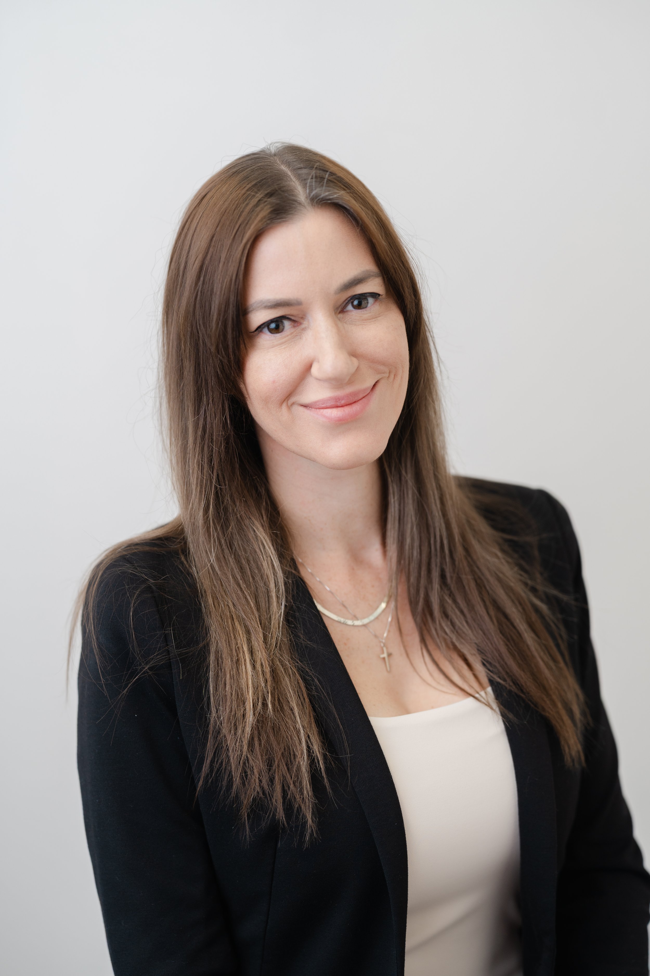 Professional headshot of a woman with long brown hair in a black blazer
