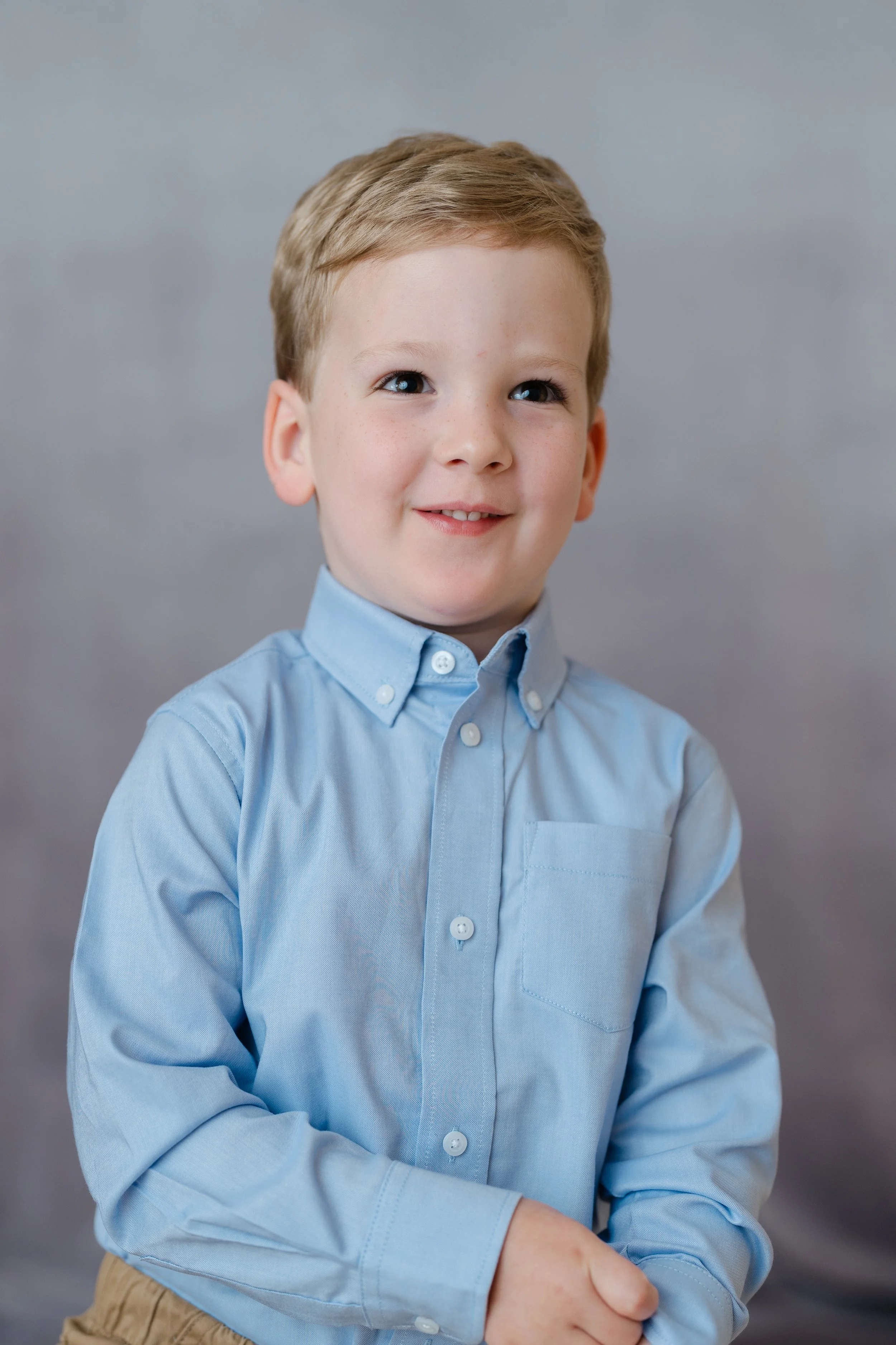 Portrait of a smiling young boy in a light blue button-down shirt
