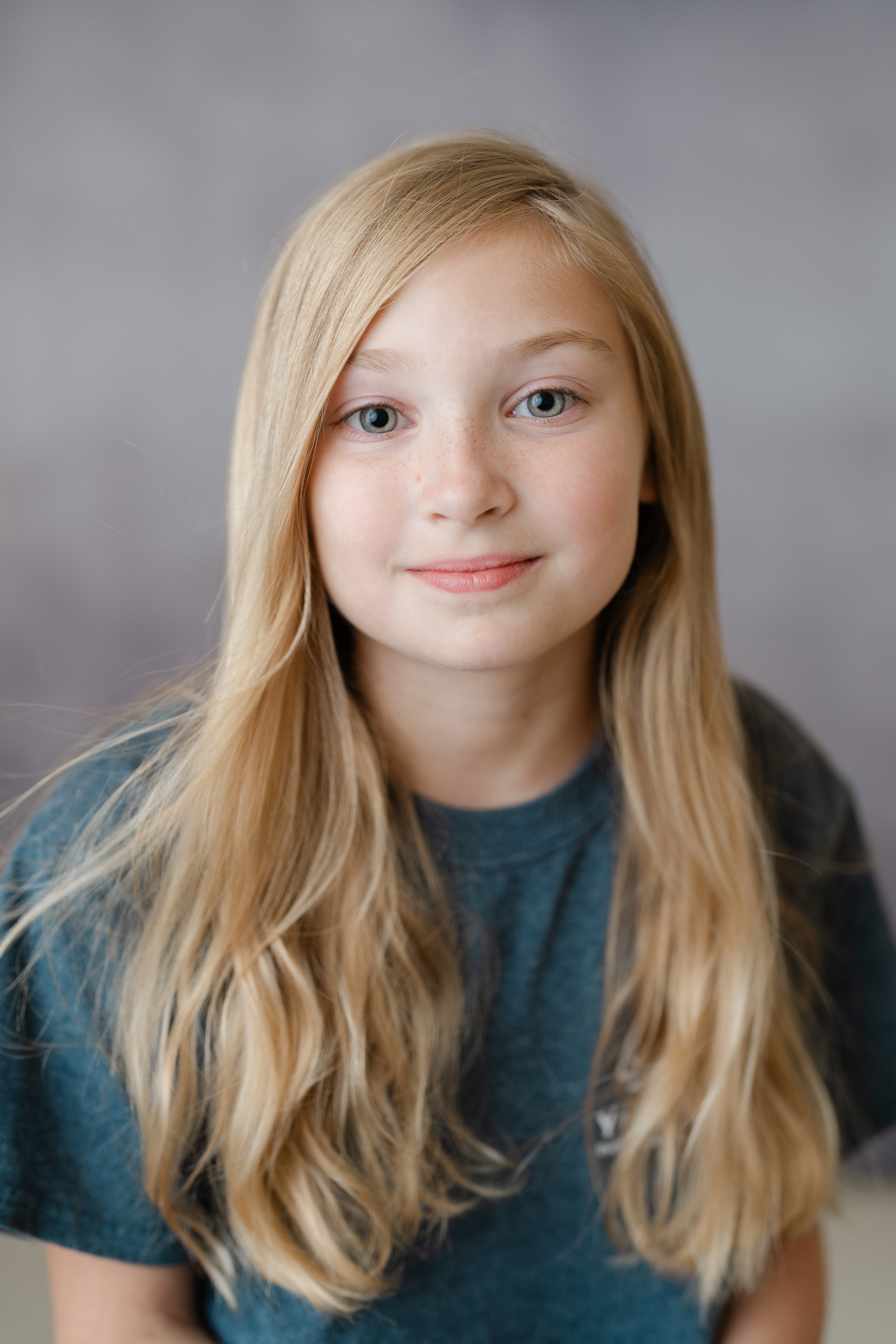 Portrait of a girl with long blonde hair in a teal top