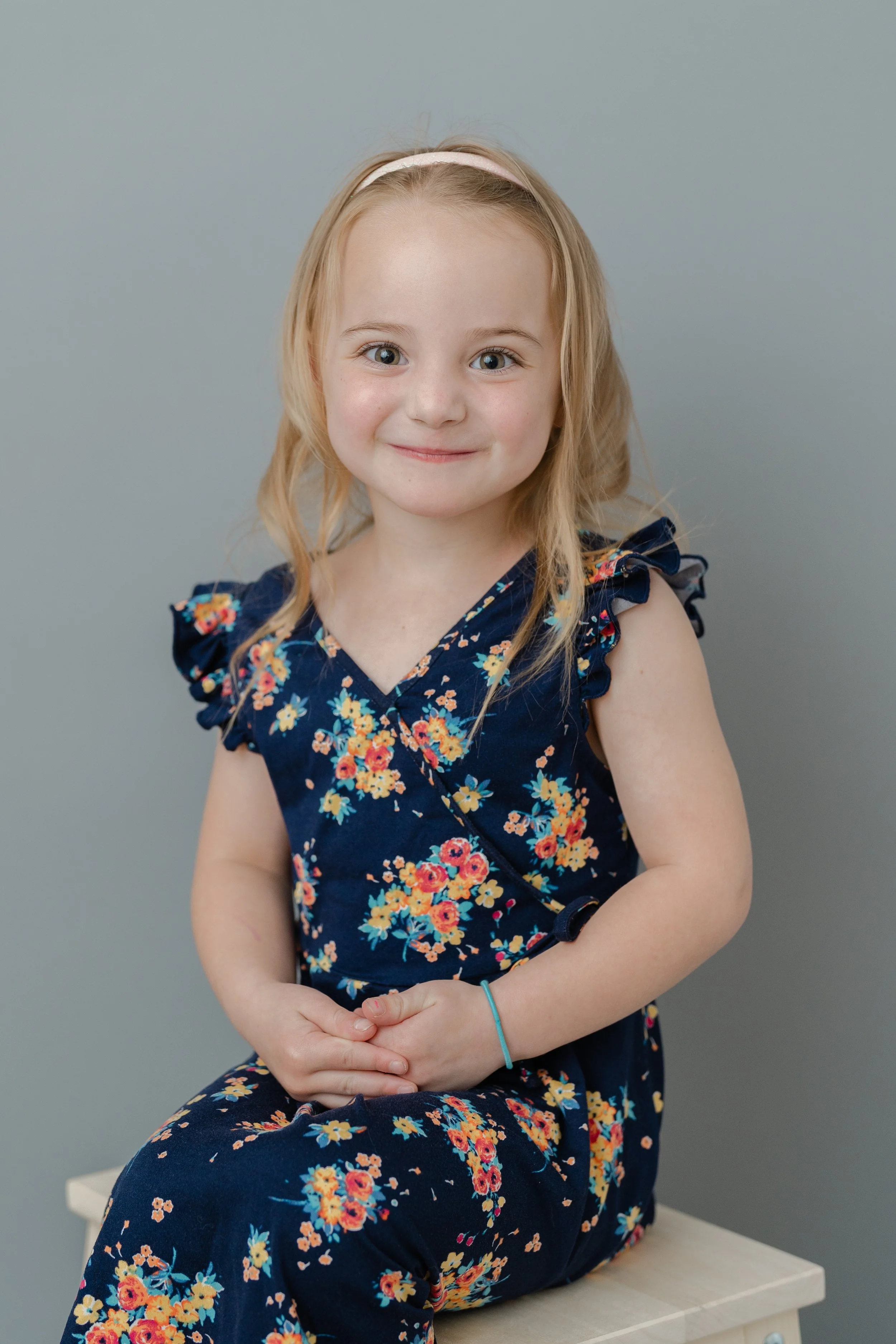 Portrait of a young girl with a headband in a navy floral dress