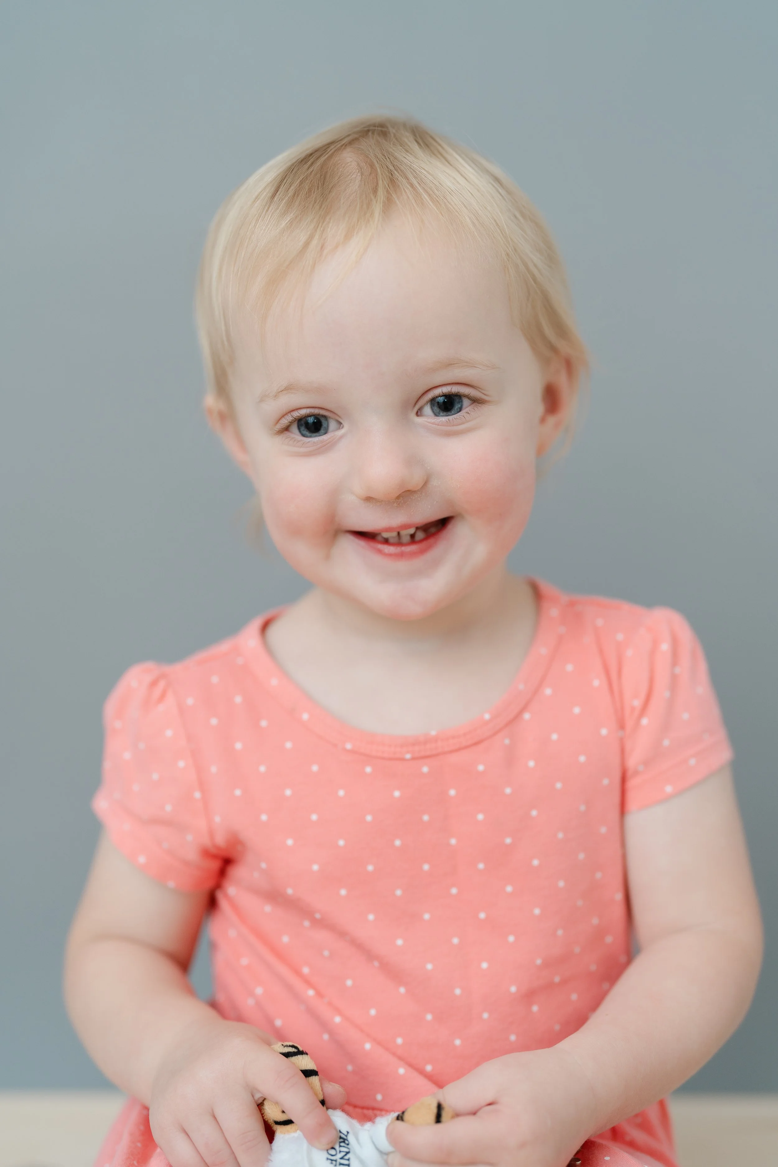 Portrait of a smiling toddler girl in a pink polka dot top