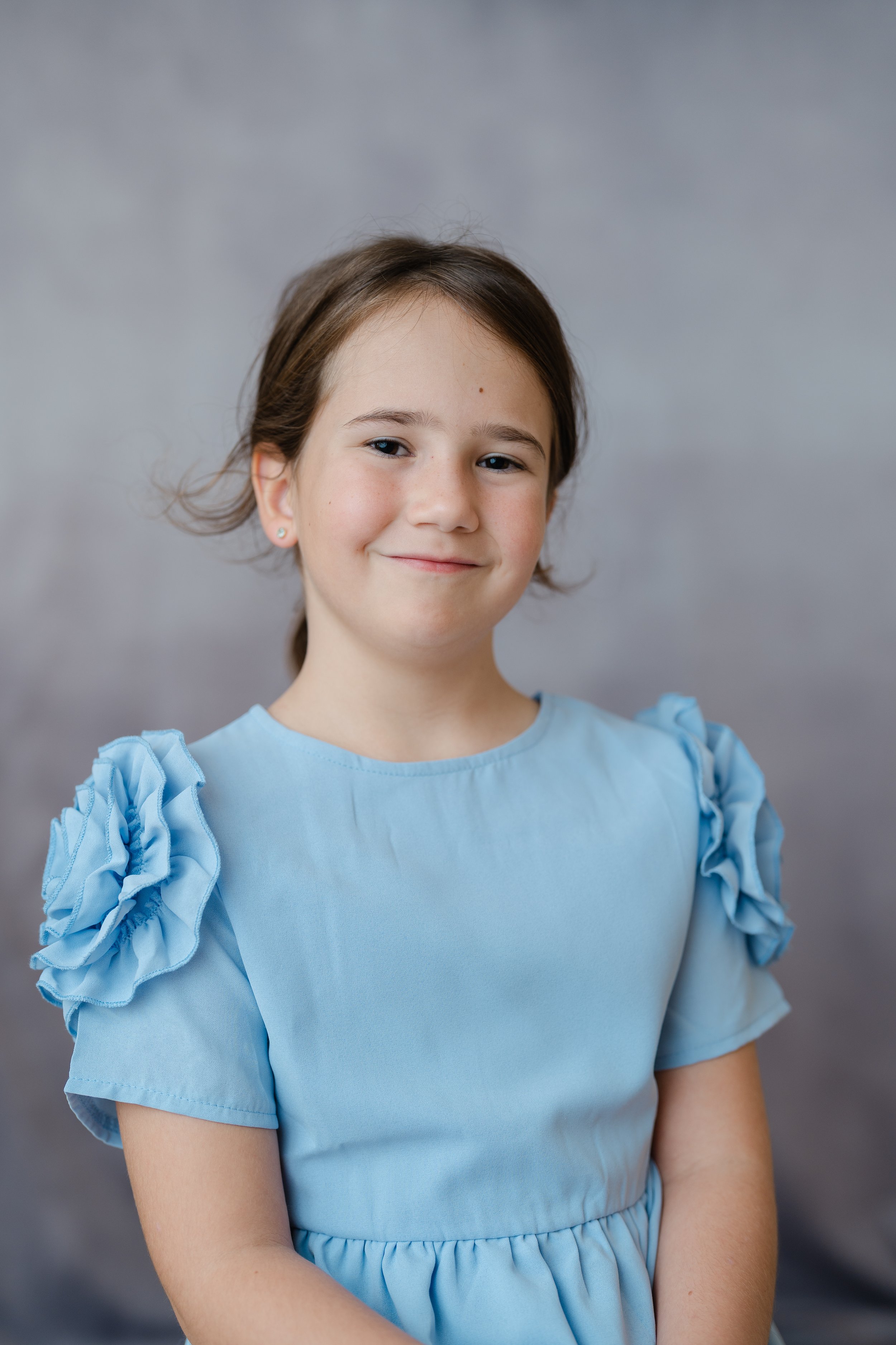 Portrait of a girl in a light blue dress with ruffled sleeves