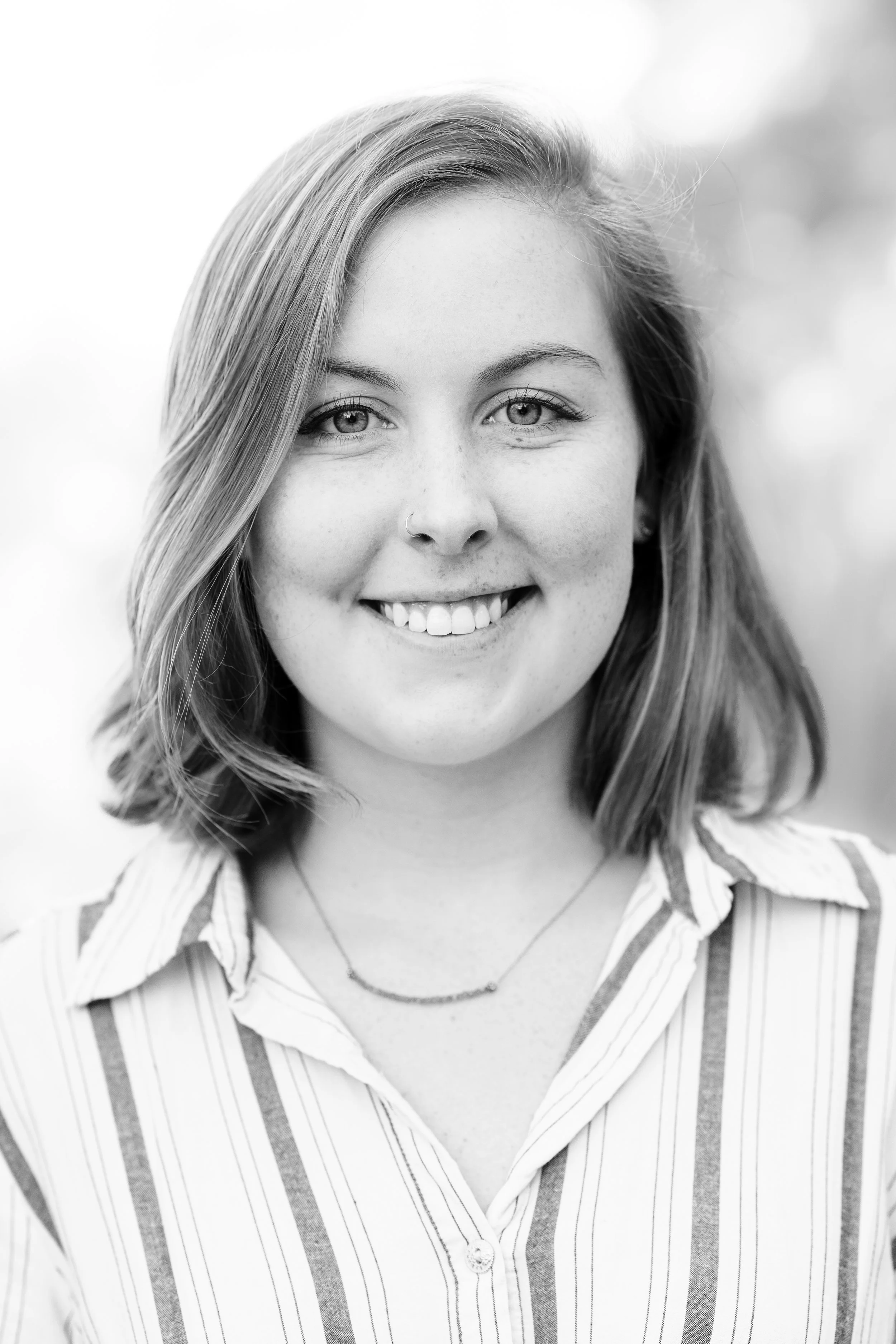 Black and white portrait of a smiling woman with shoulder-length hair in a striped shirt