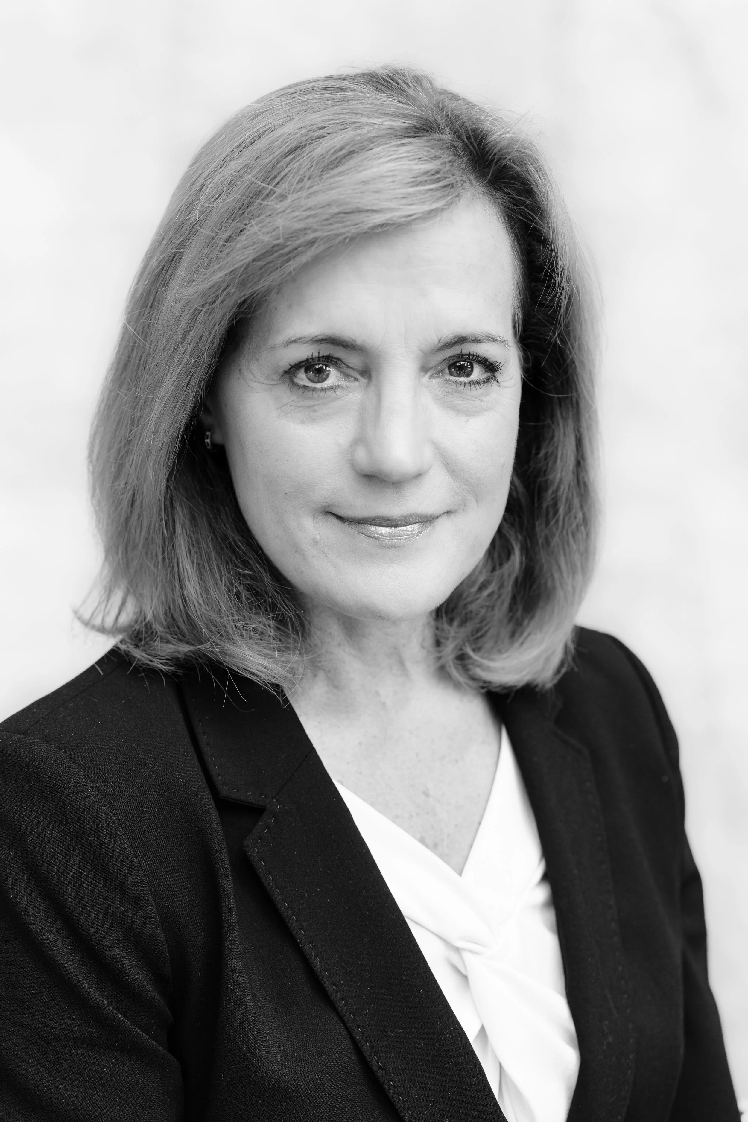 Black and white headshot of a woman with shoulder-length hair in a dark blazer