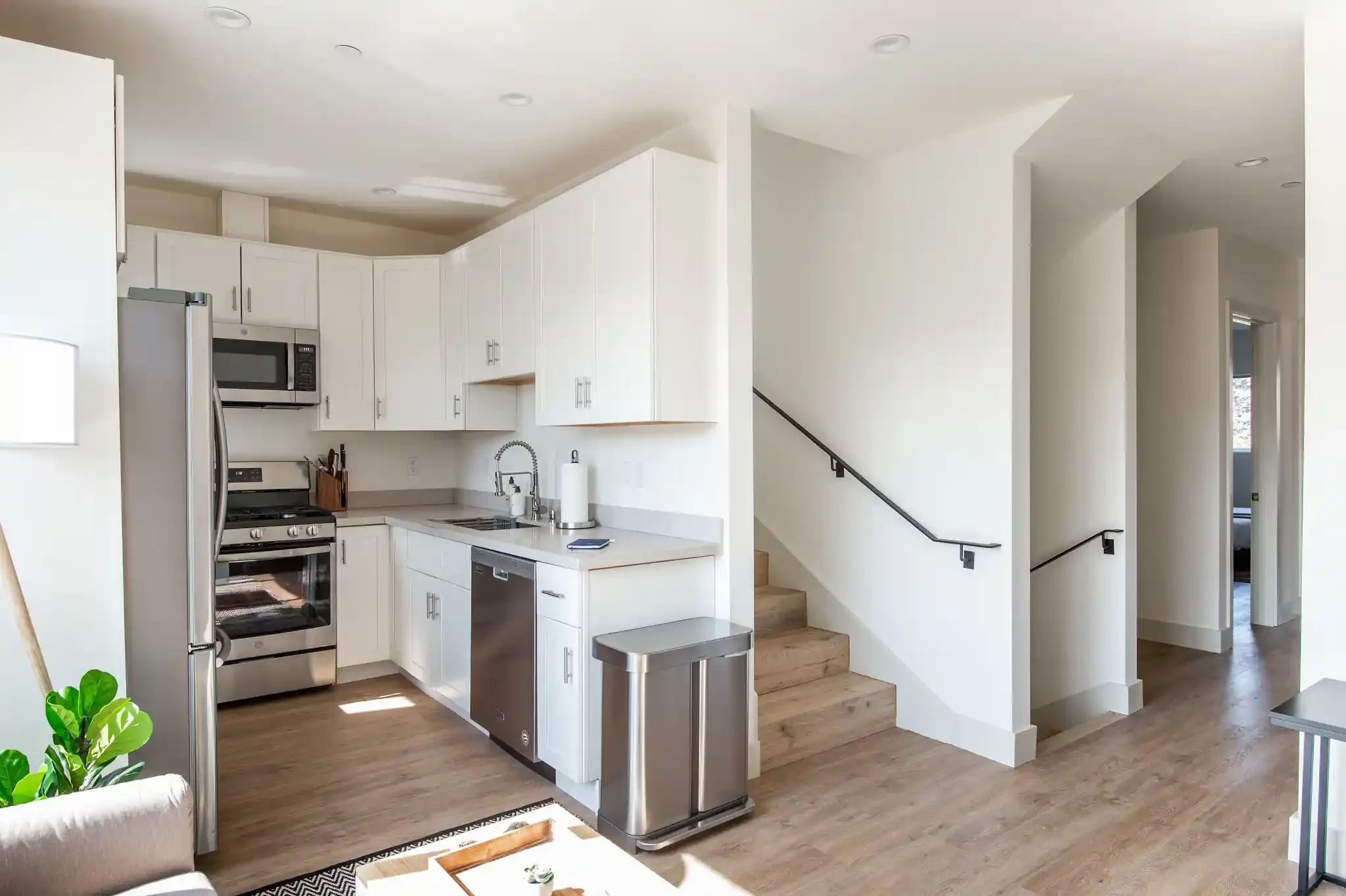Kitchen with stainless appliances and staircase, showing duplex layout
