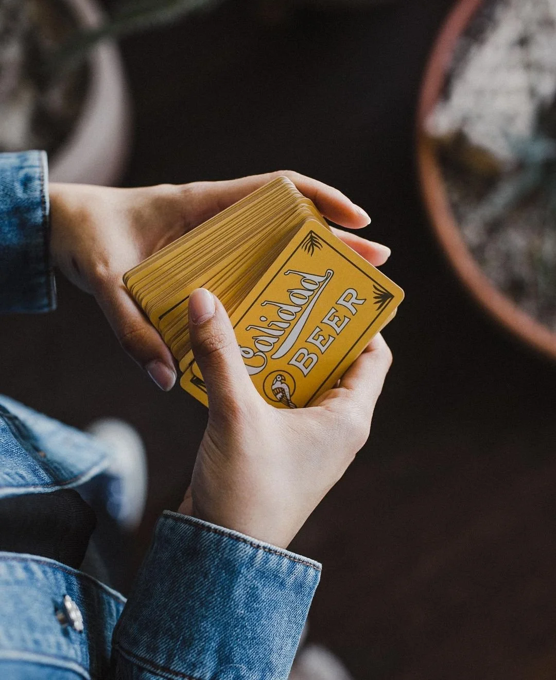 A person holding a stack of yellow playing cards with the words 'Cordially BEER' printed on them.