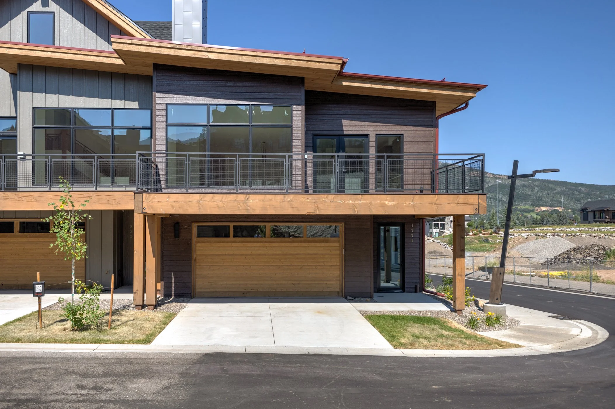 Modern townhouse with balcony, garage, and sloped roof on a clear day.