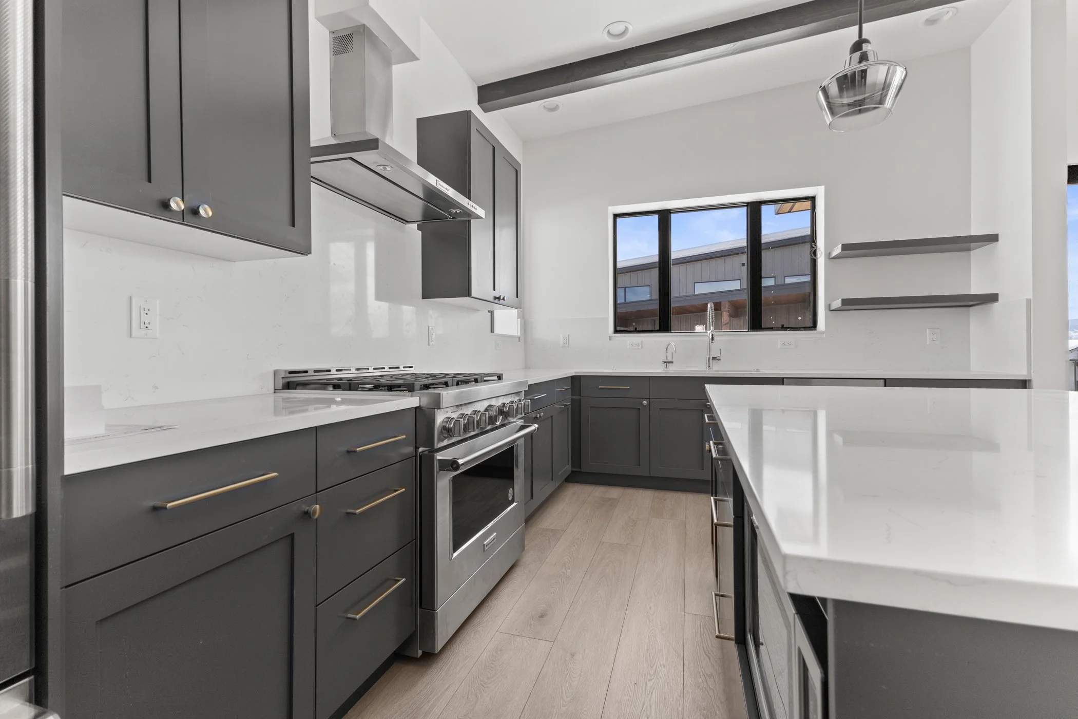 Modern kitchen with dark cabinets, stainless steel appliances, and white countertops.