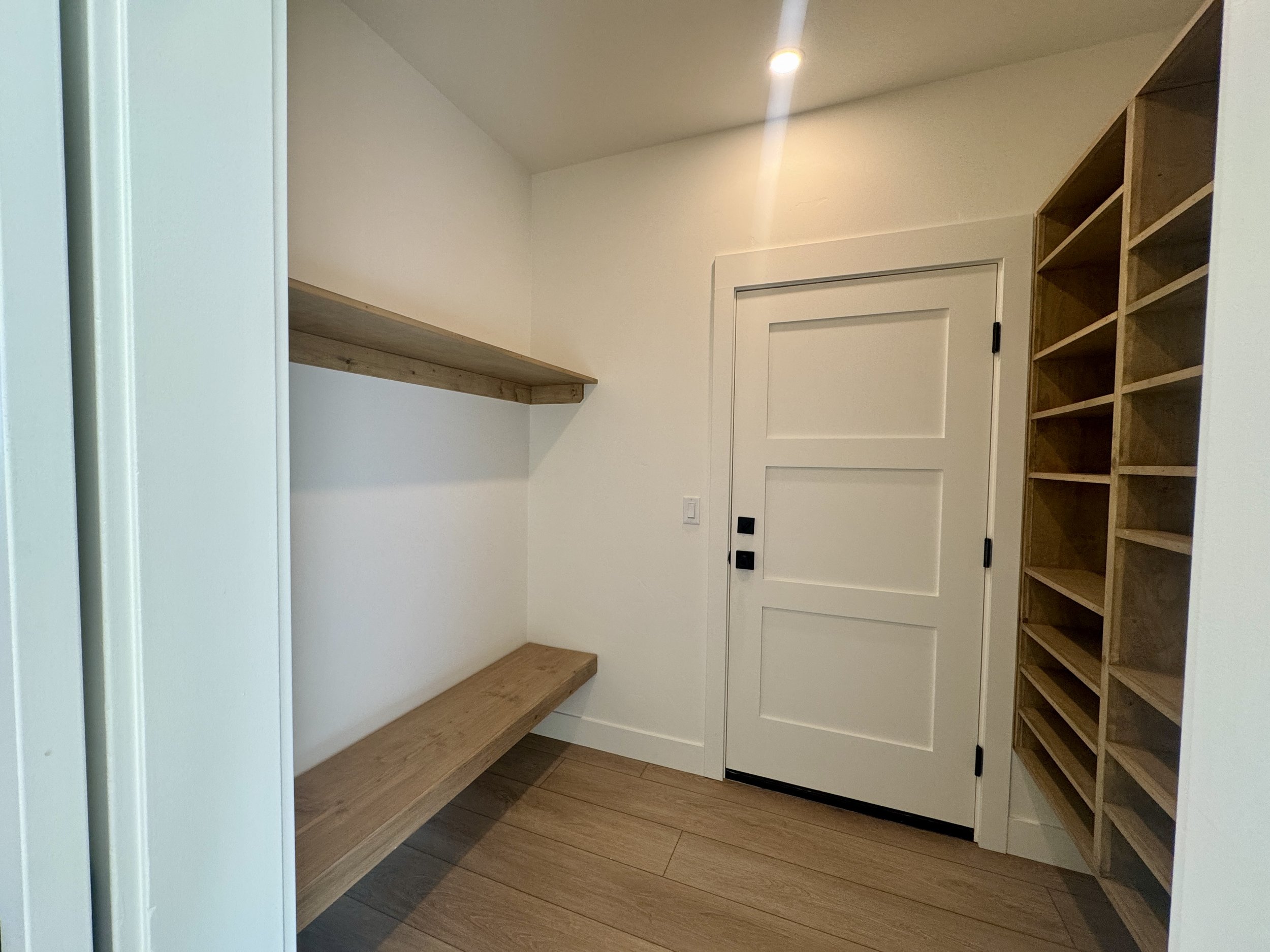 Empty closet with wooden shelves and door