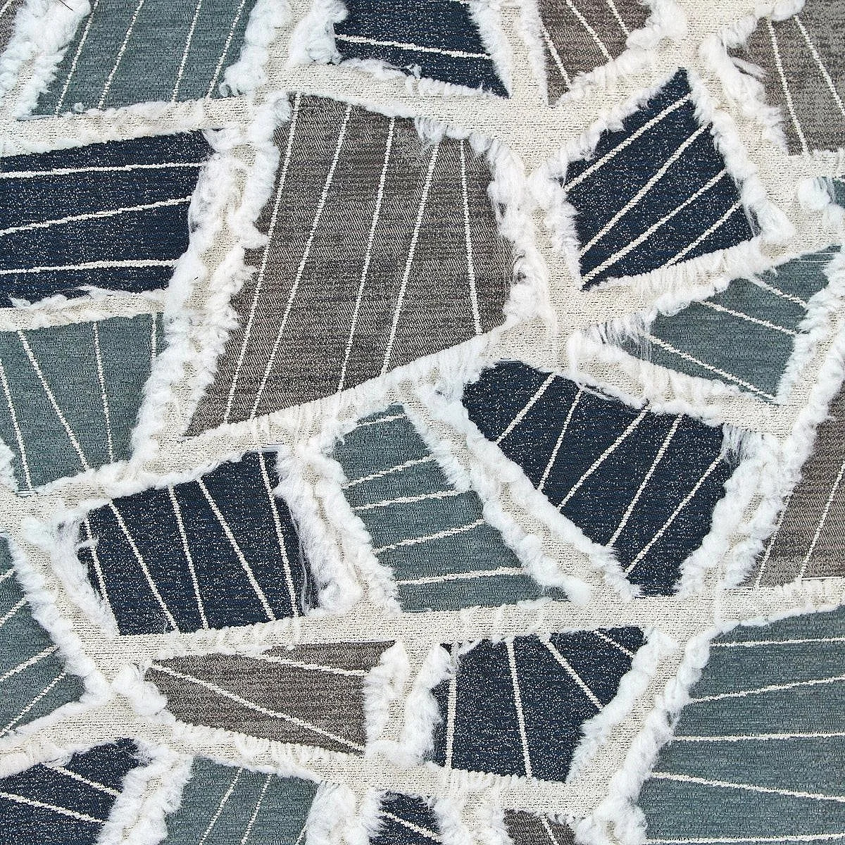 Abstract geometric fabric pattern with irregular shapes, blue, gray, and green tones, lined with white trim.