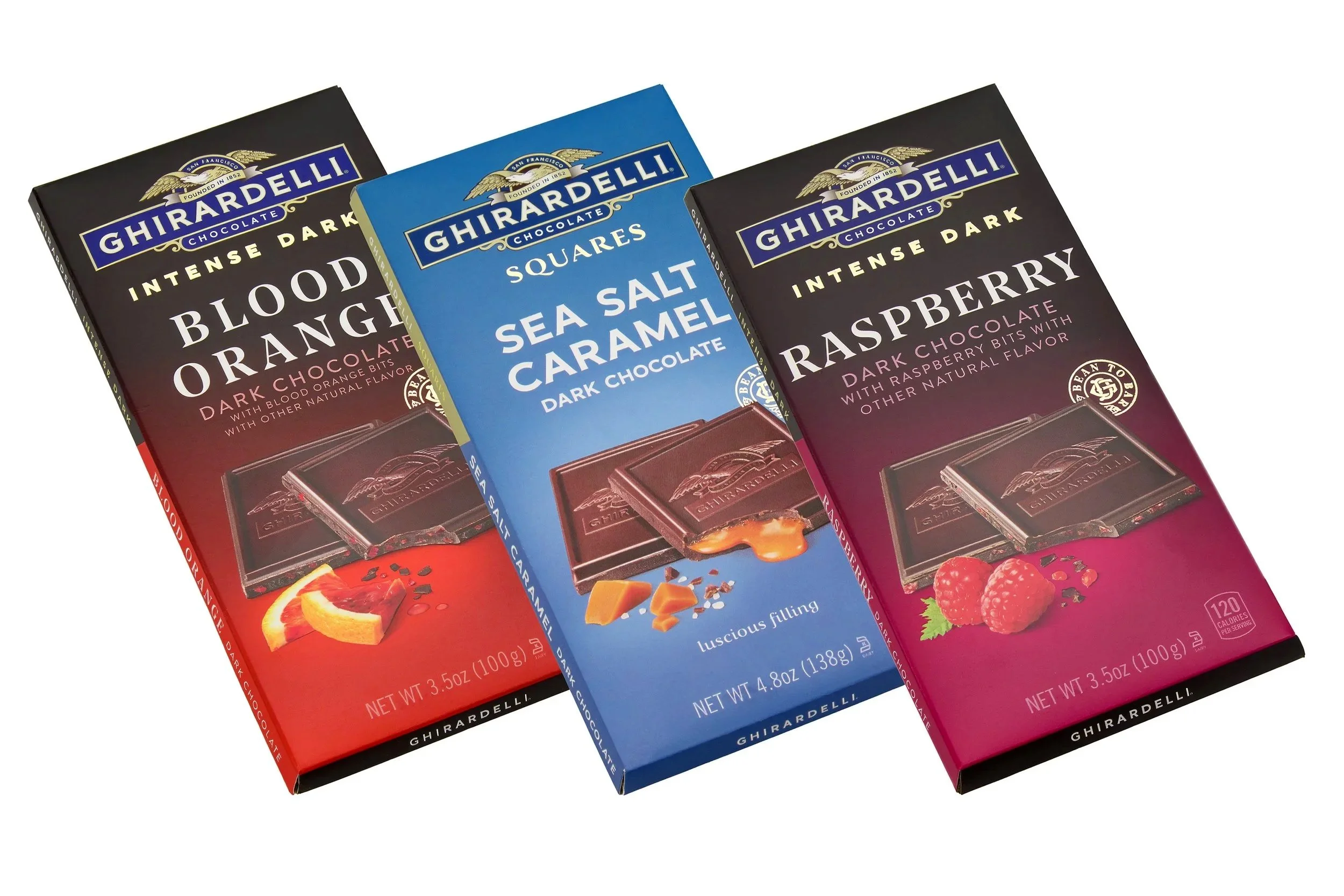 Pack shot of three boxes of Ghirardelli chocolate in flavors blood orange, sea salt caramel, and raspberry, arranged side by side.