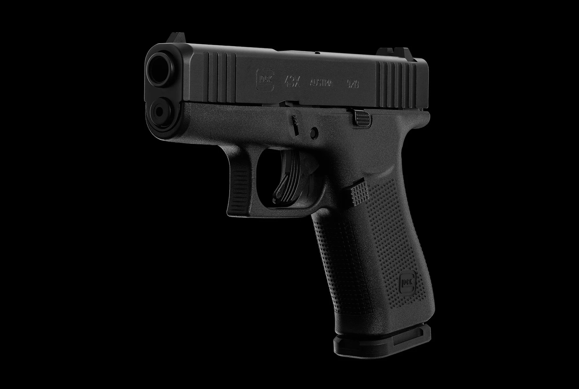 A black semi-automatic pistol with a textured grip and slide, set against a black background.