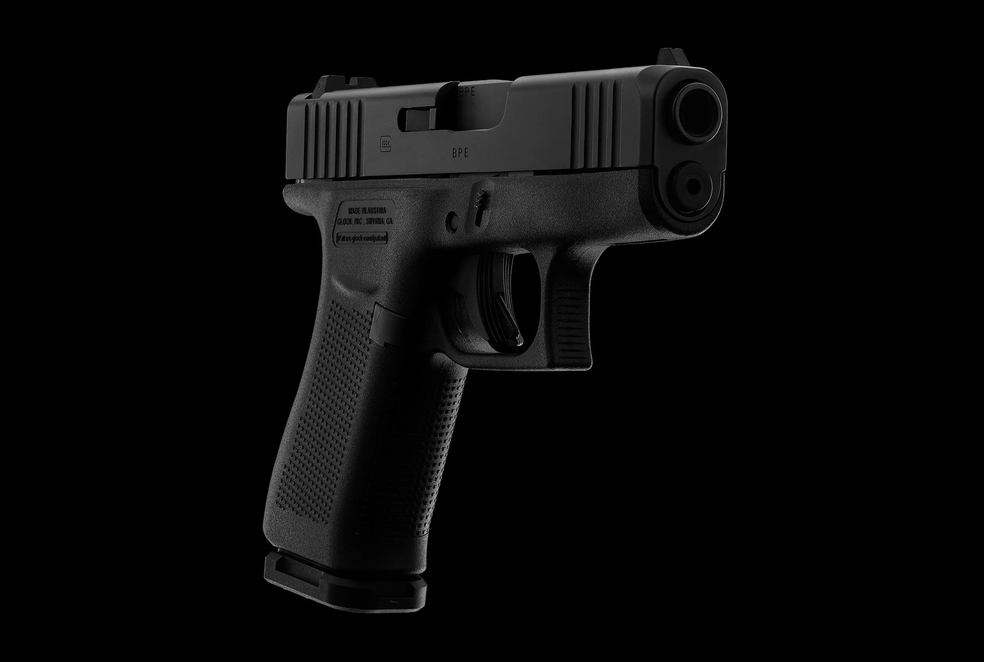 Black semi-automatic handgun with textured grip against black background.