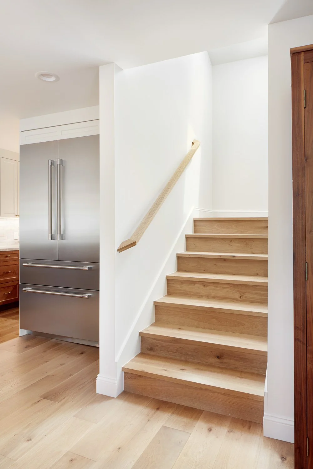 Clean wood staircase with modern handrail and bright transitions – custom home remodel.