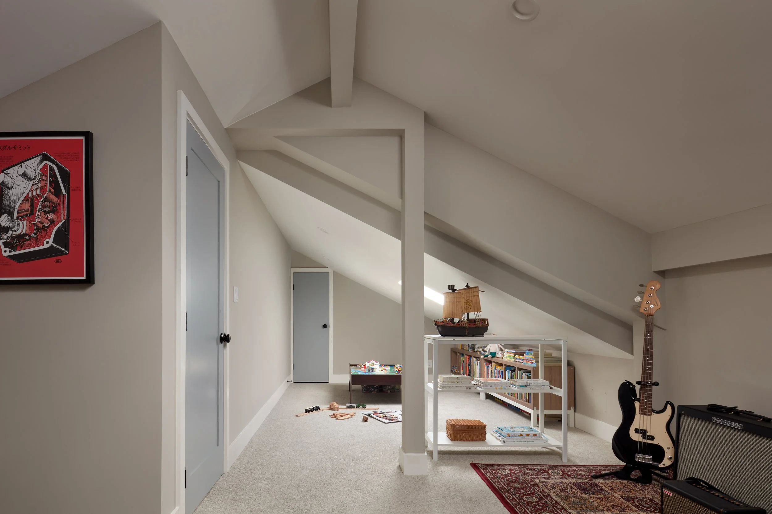 Finished attic bonus room with sloped ceilings, built-in shelving, kids play area, and flexible family space design.