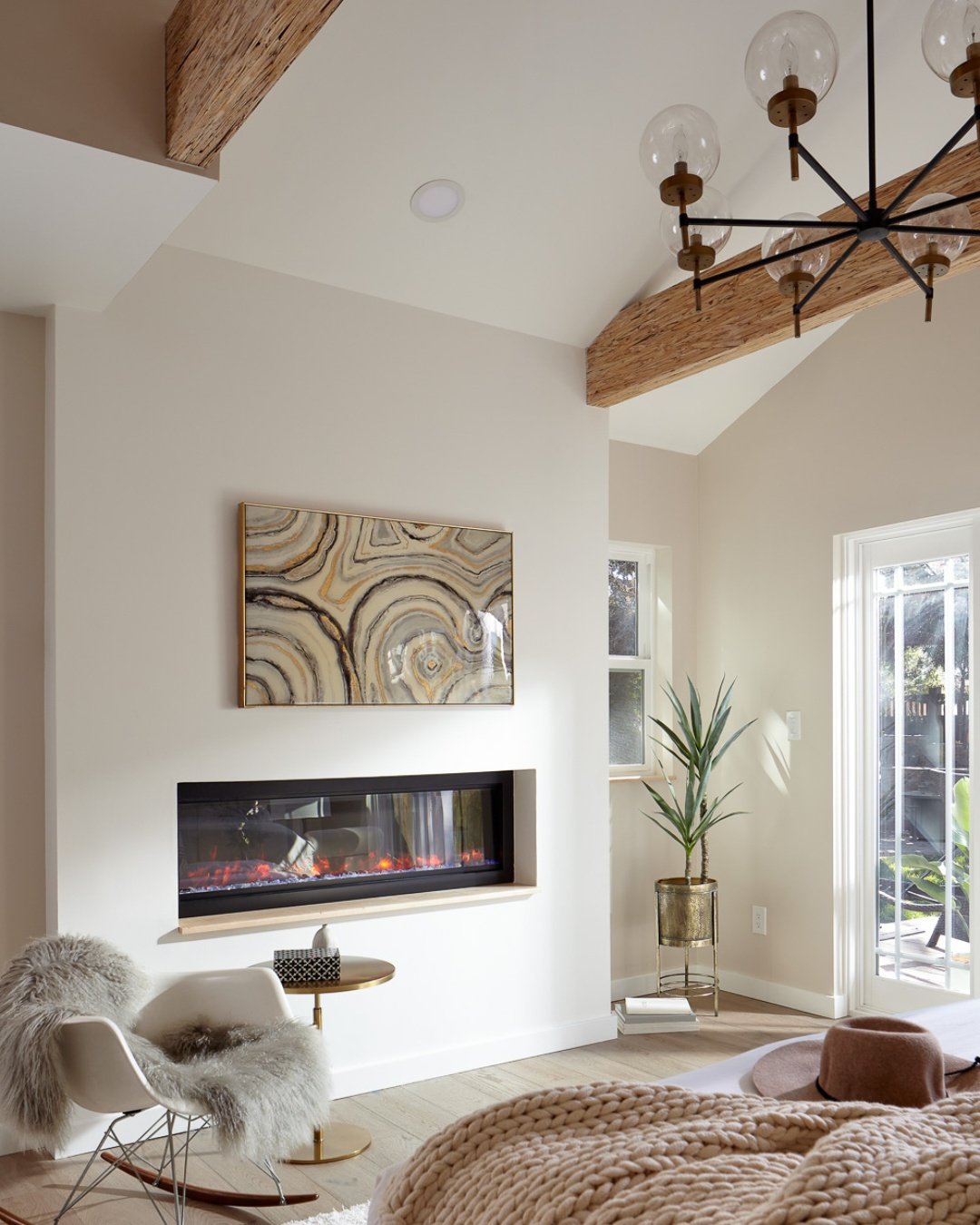Waking up in paradise, right at home. ✨ This gorgeous primary suite addition is the ultimate retreat. High vaulted ceilings paired with rustic, textured wood beams create an airy yet grounded atmosphere, while the modern built-in fireplace adds a lay