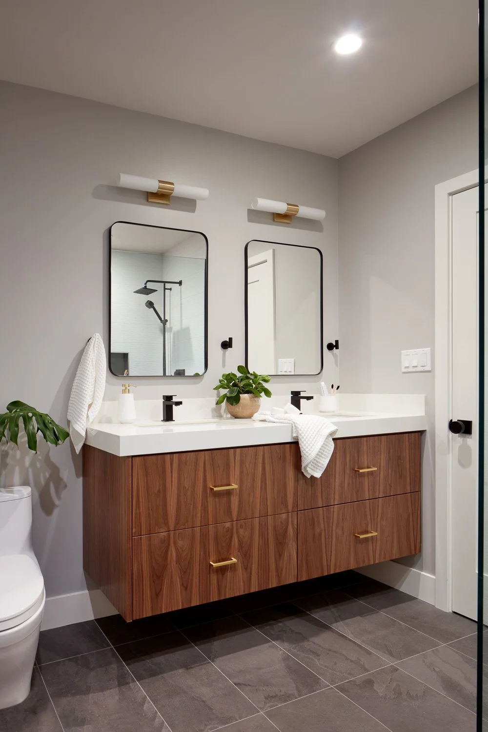 Warm wood cabinetry and modern lighting elevate this thoughtfully designed bathroom in a custom new construction home.