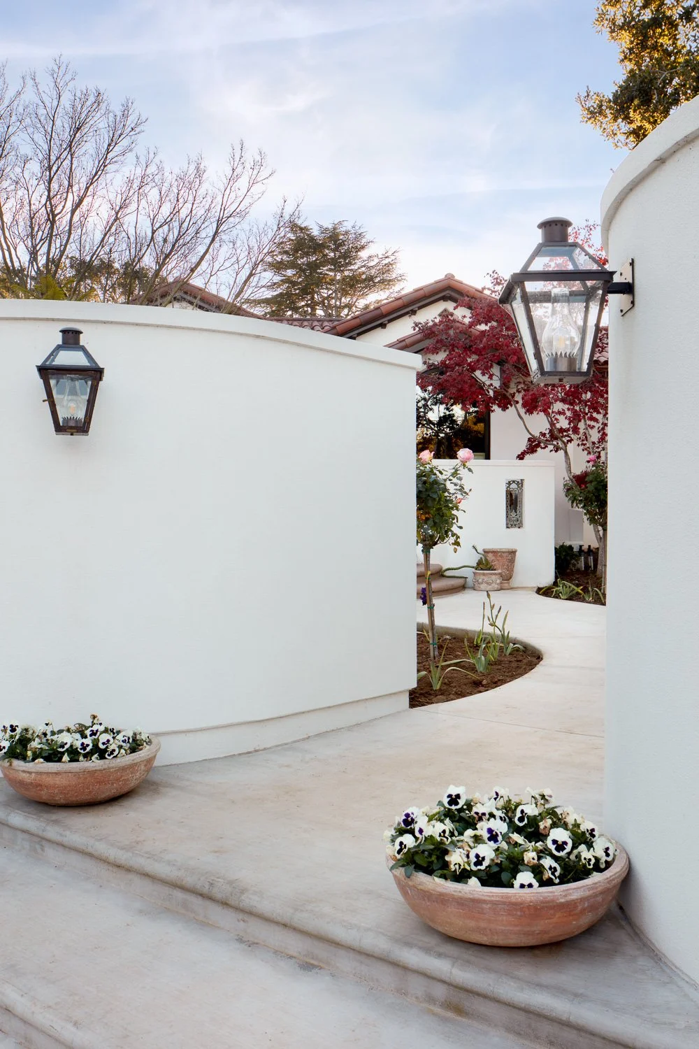 A serene courtyard approach featuring Spanish-style curves, soft landscaping, and custom lighting from this high-end San Mateo renovation