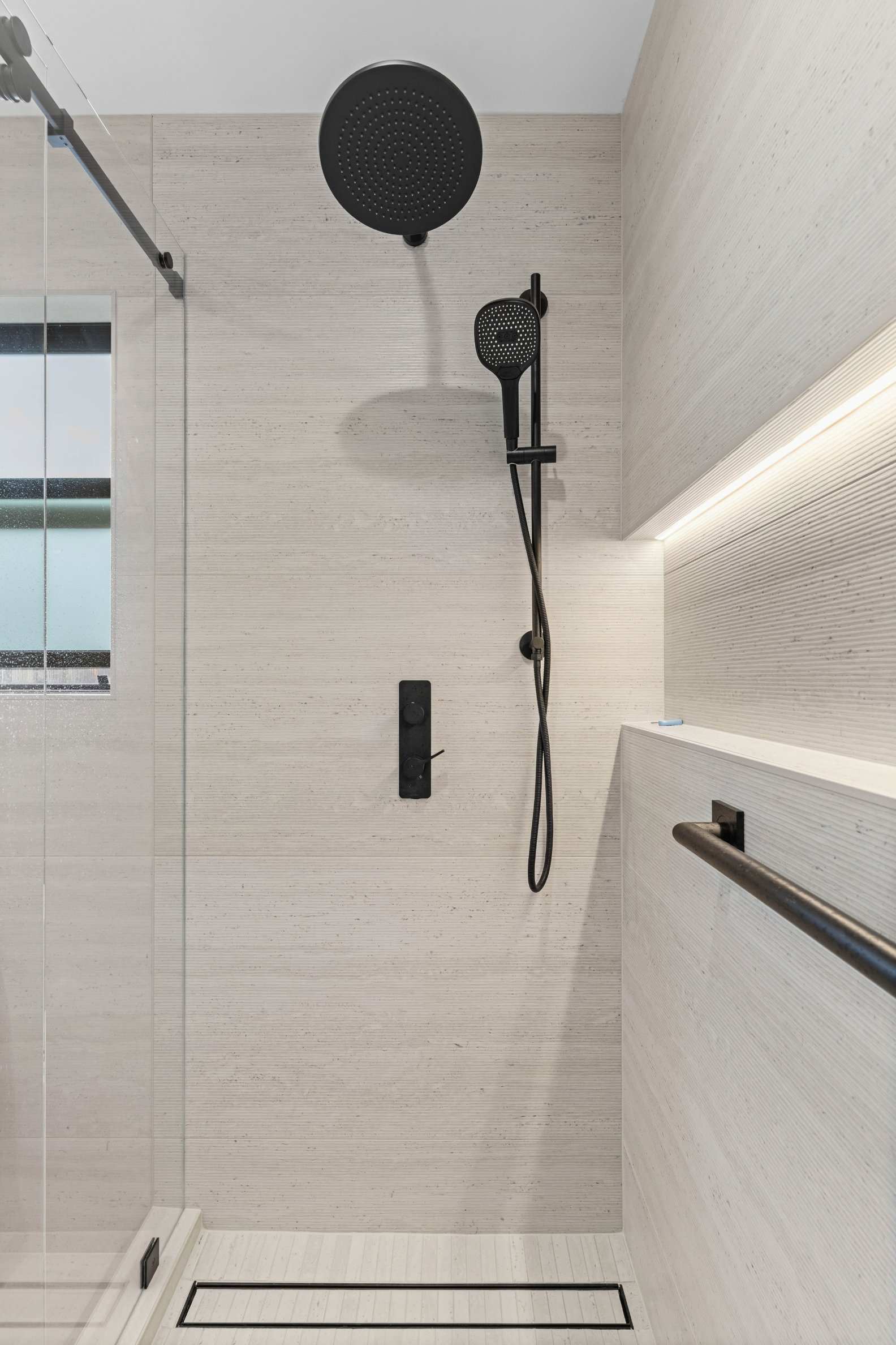 Spa-inspired walk-in shower with matte black fixtures, illuminated niche, and large-format tile for a sleek, modern finish.