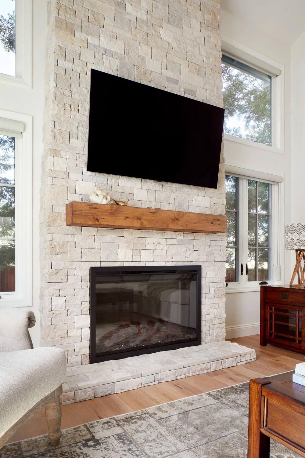 Floor-to-ceiling fireplace with rustic mantel and modern finish – custom home remodel.