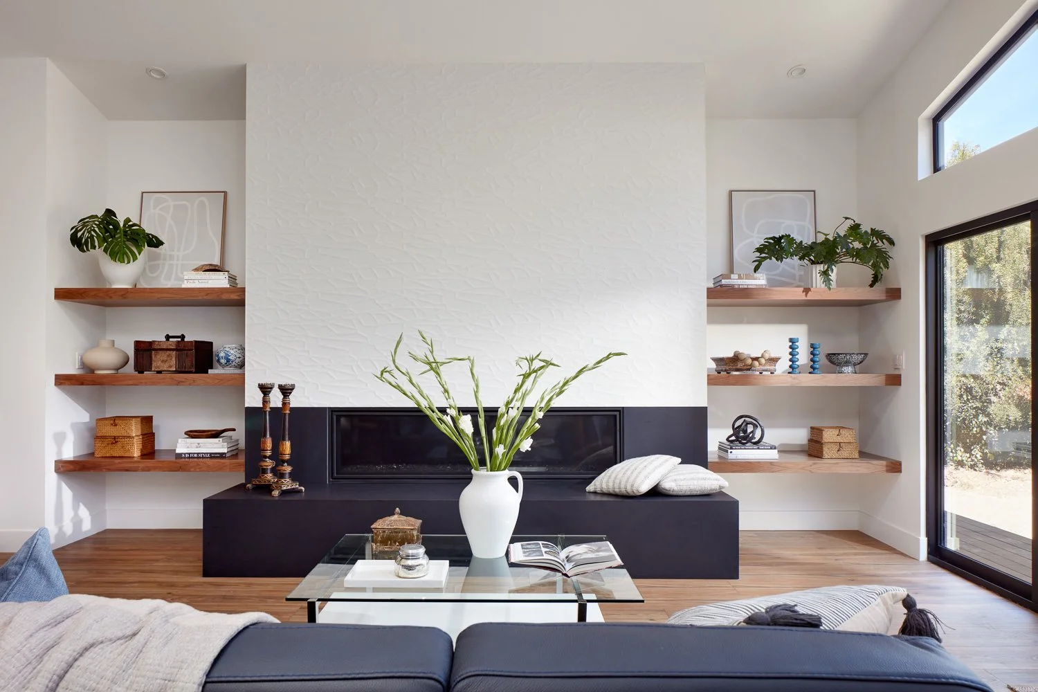 A light-filled living space with custom fireplace and built-ins, designed as part of a luxury new construction home.