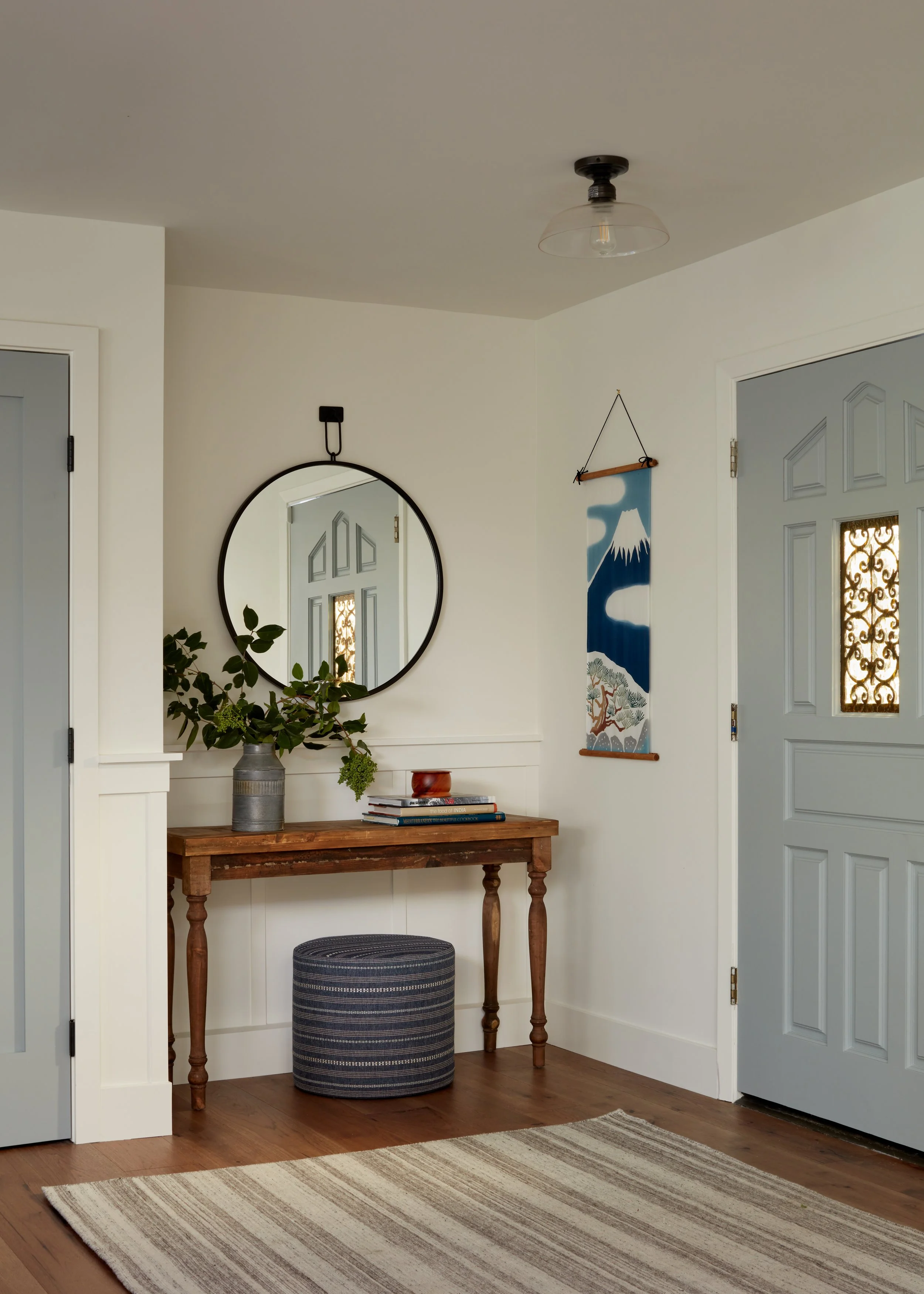 Entry hall vignette featuring custom millwork, decorative wall art, wood console, and soft neutral finishes.