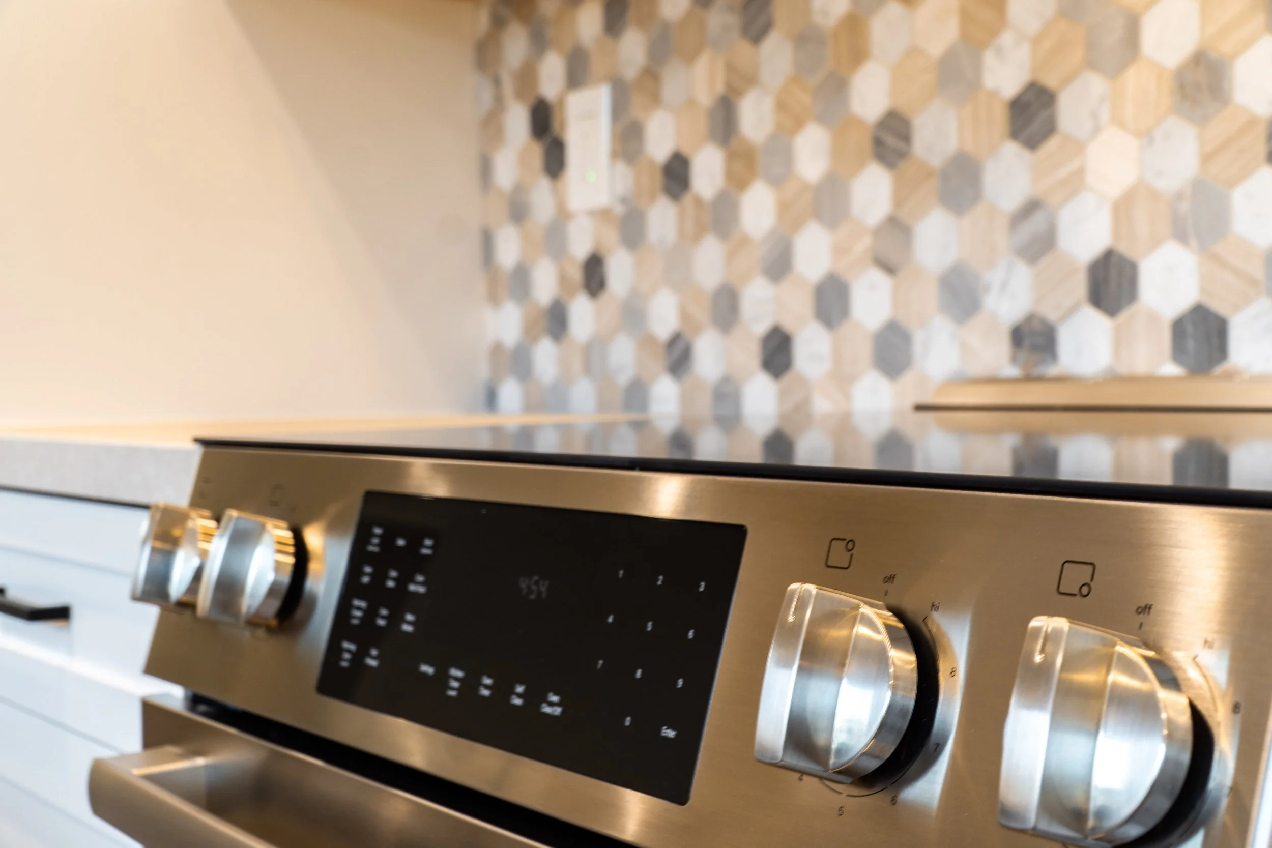 Stainless steel range with modern control panel and hex tile backsplash in a remodeled San Jose kitchen.