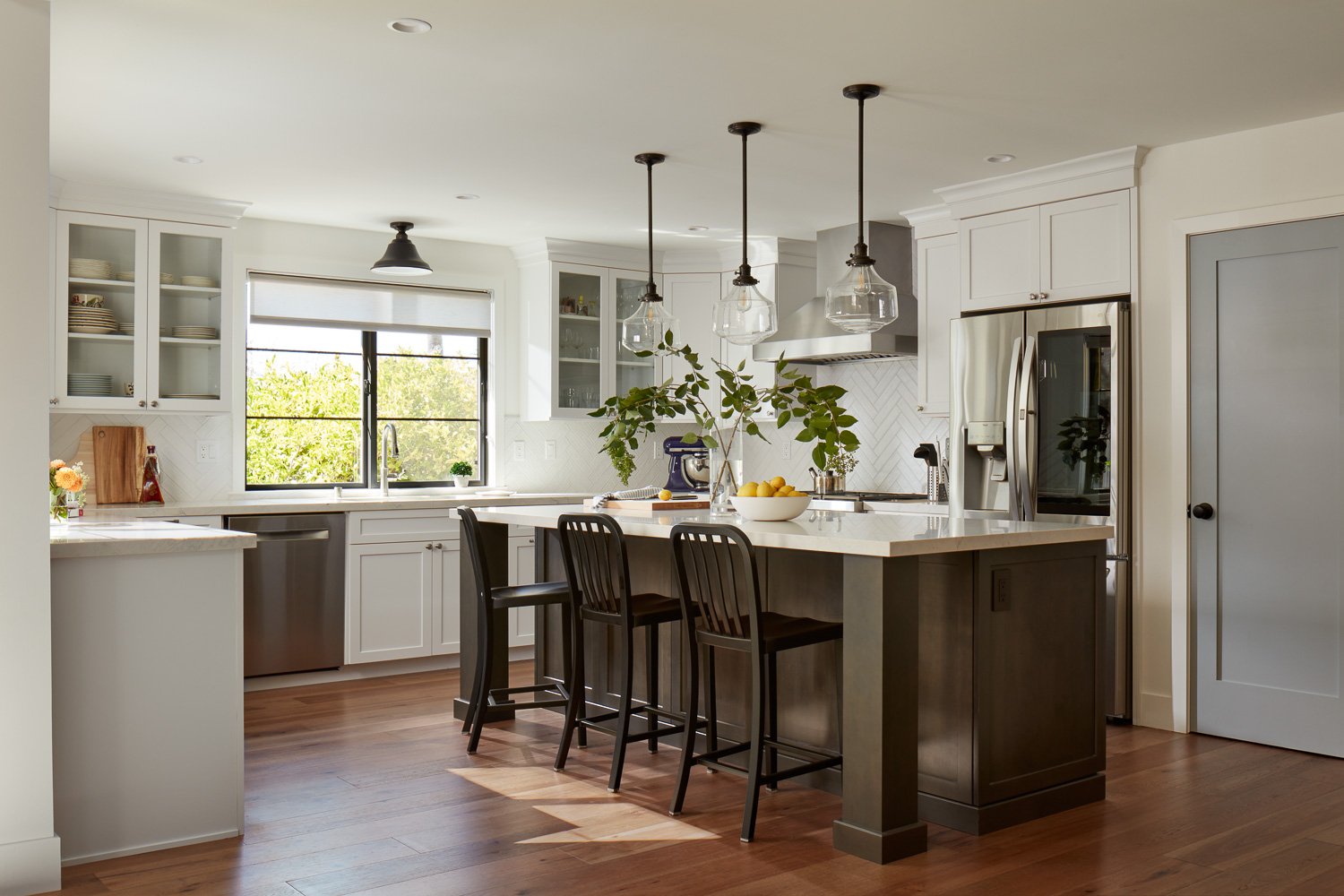 Modern kitchen remodel in Pacifica featuring white cabinetry, large island seating, pendant lighting, and hardwood floors.