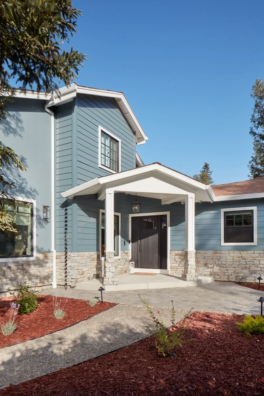 Front exterior with new siding, stone veneer, and landscaping – custom home remodel.