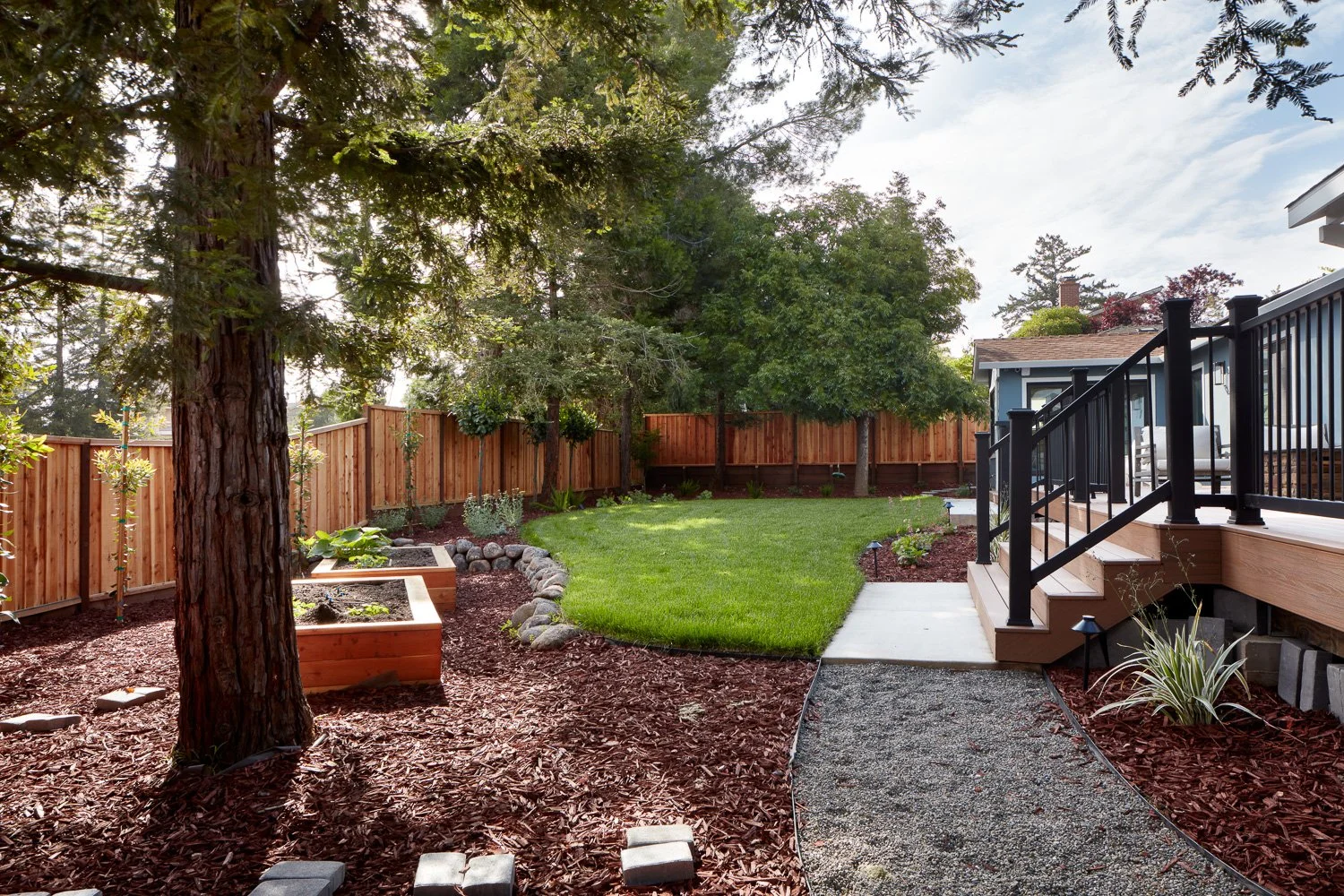 Lush backyard with curved lawn, planters, and custom hardscape – custom home remodel.