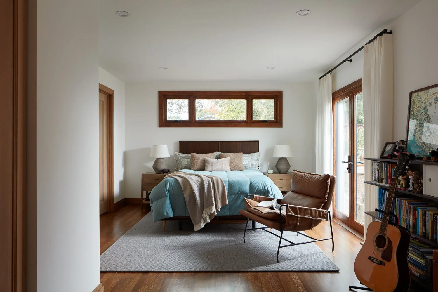 Bright primary bedroom remodel featuring warm wood floors, custom windows, and a calm, comfortable layout for modern living.