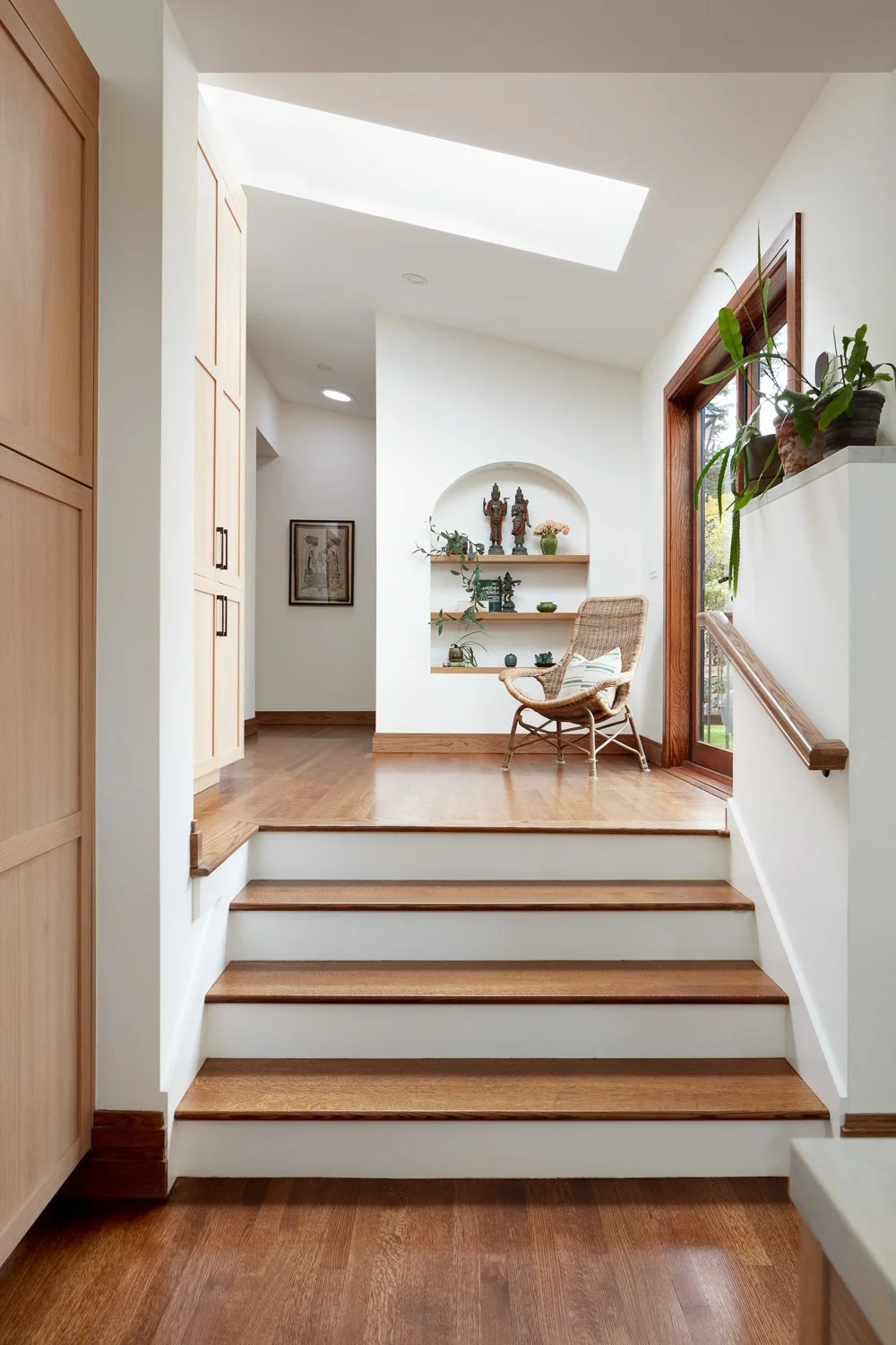 Sunlit transition space with skylight and custom wood stairs, adding warmth, flow, and architectural character to this full home remodel.