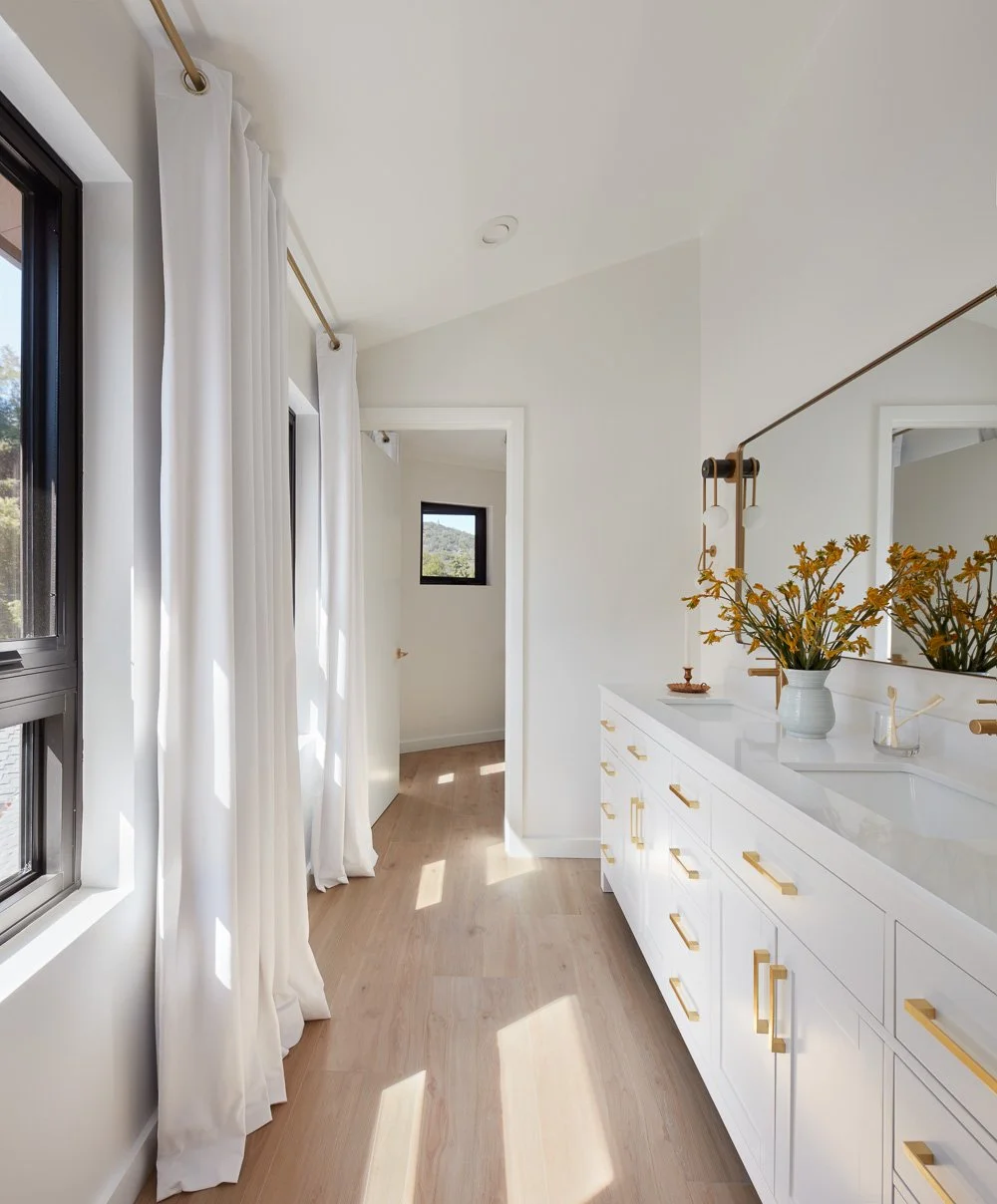 A calm, light-filled bathroom with custom cabinetry, brass accents, and a spa-like flow.