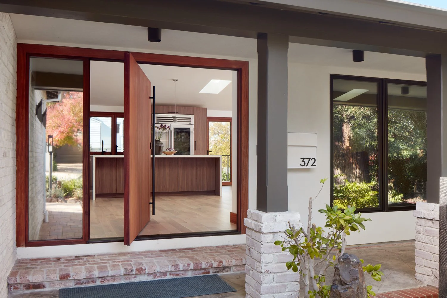 Welcoming entryway with custom wood front door and covered porch, blending modern architecture with warm natural materials.