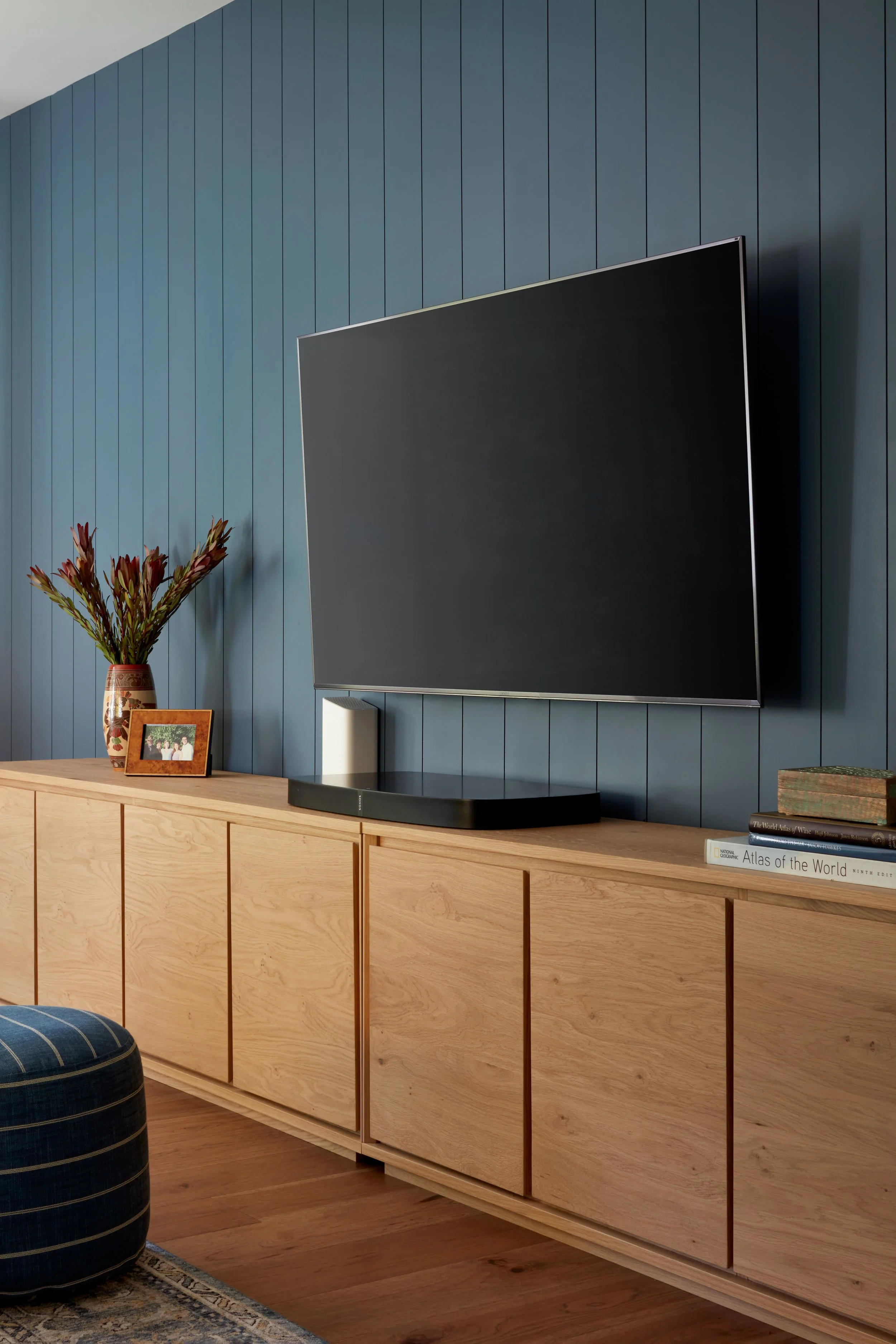 Media wall with custom wood cabinetry, mounted TV, and blue accent wall in a modern family room.