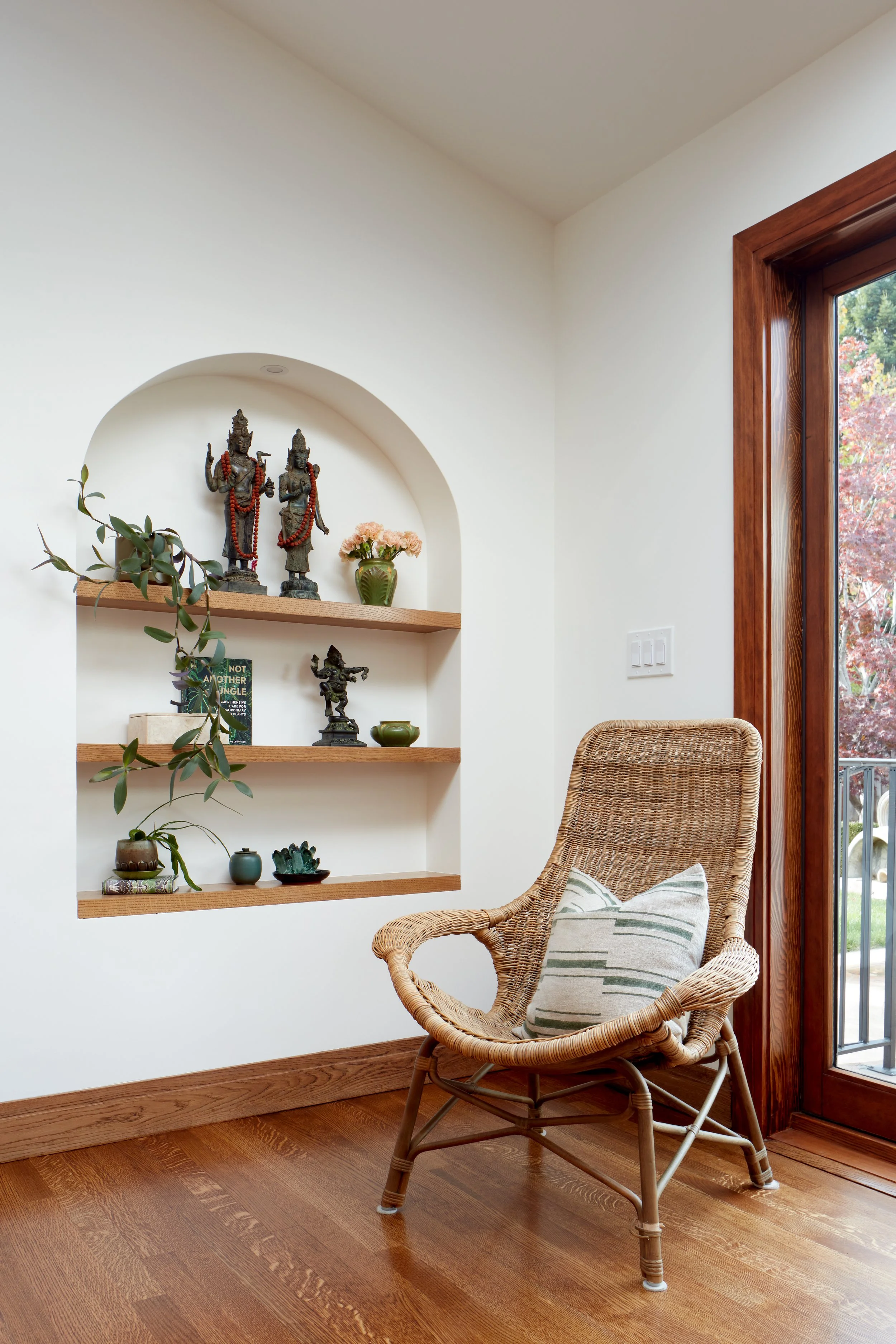 Custom arched niche and built-in shelving create a serene reading nook, blending Spanish-style charm with modern home renovation design.