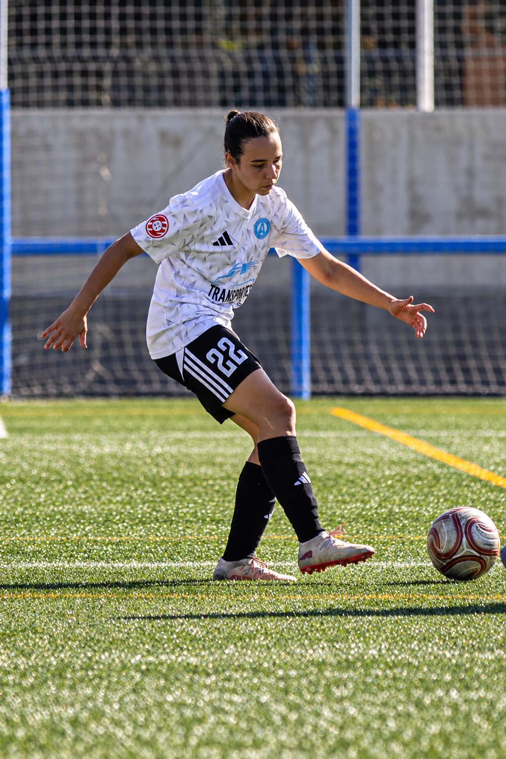 Jugadora de fútbol con uniforme del Atlético de Madrid en un campo de césped.