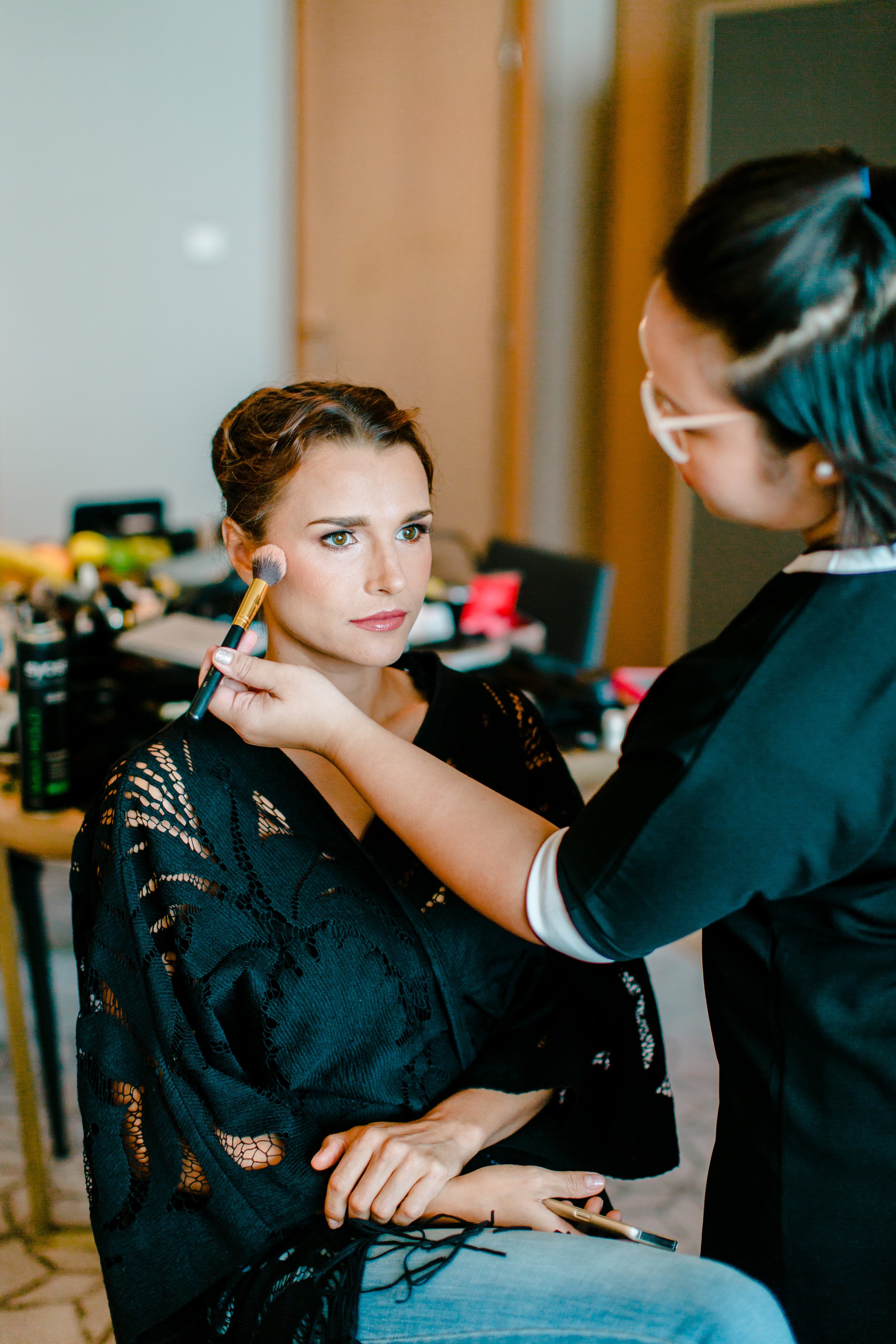 A woman getting her makeup done by a makeup artist.