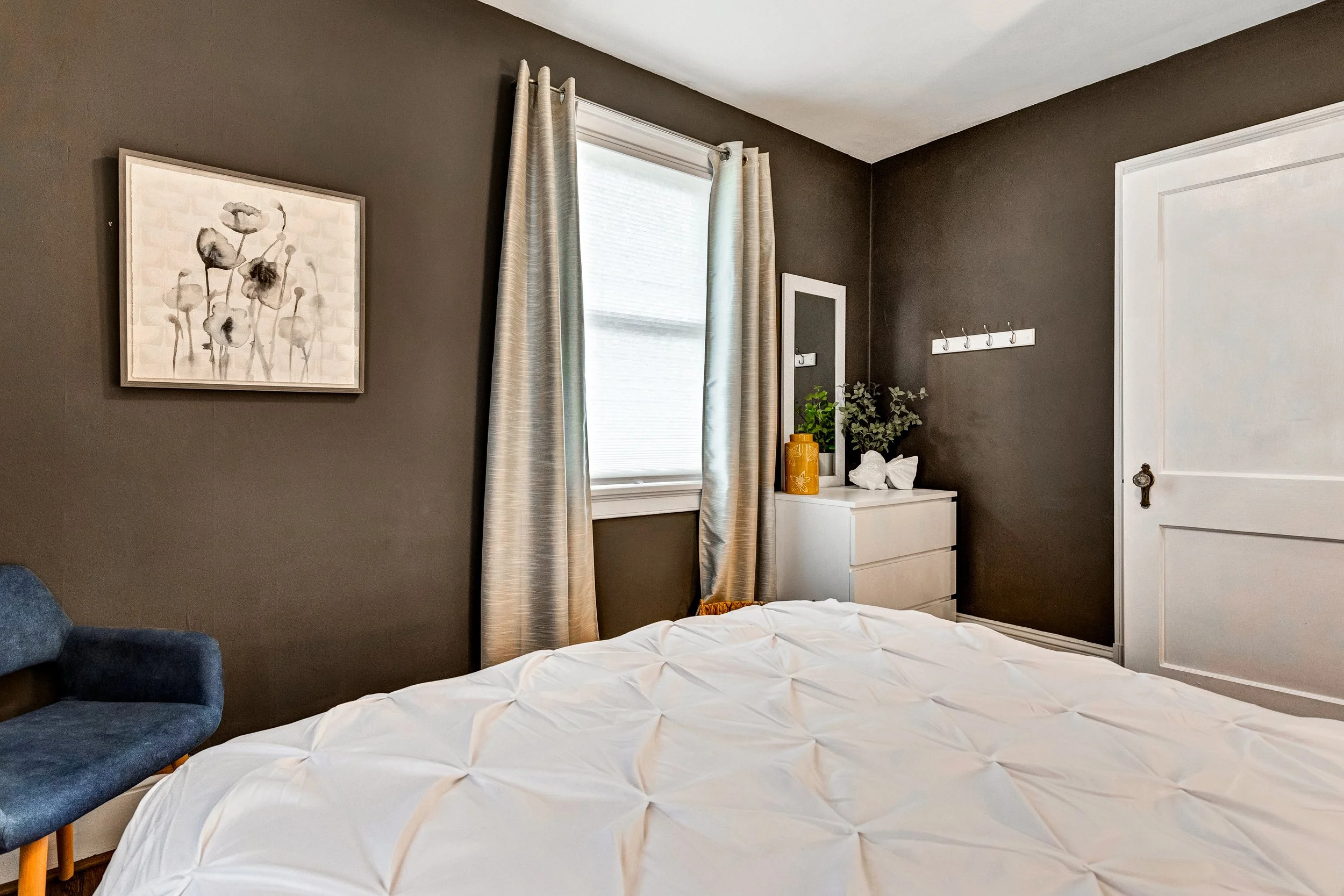Designer bedroom with beautiful art, a comfortable bed and plenty of natural light.