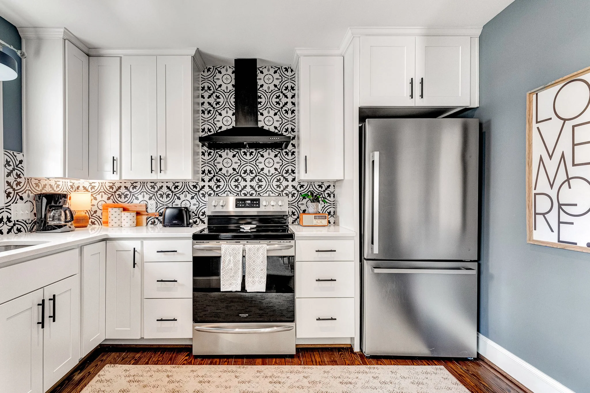 Fully equipped modern kitchen with stainless steel appliances, designer tile backsplash, and gourmet cookware.