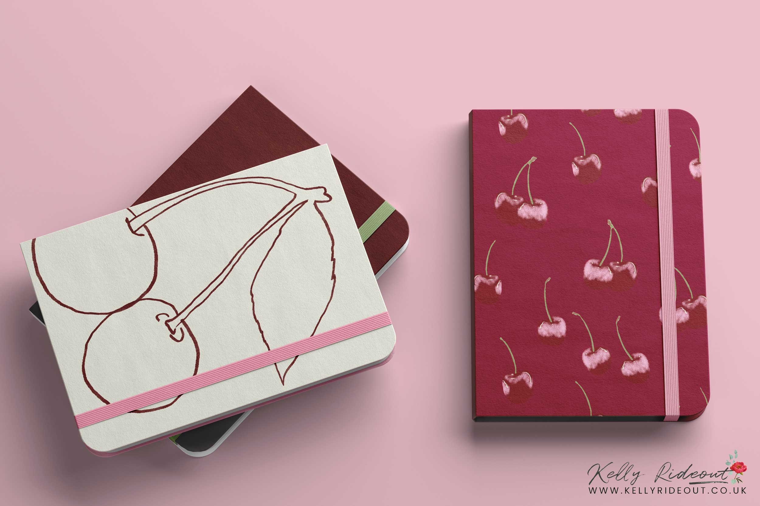 A set of colorful notebooks, with one featuring a cherries pattern and another with a cherry illustration on a pink background.