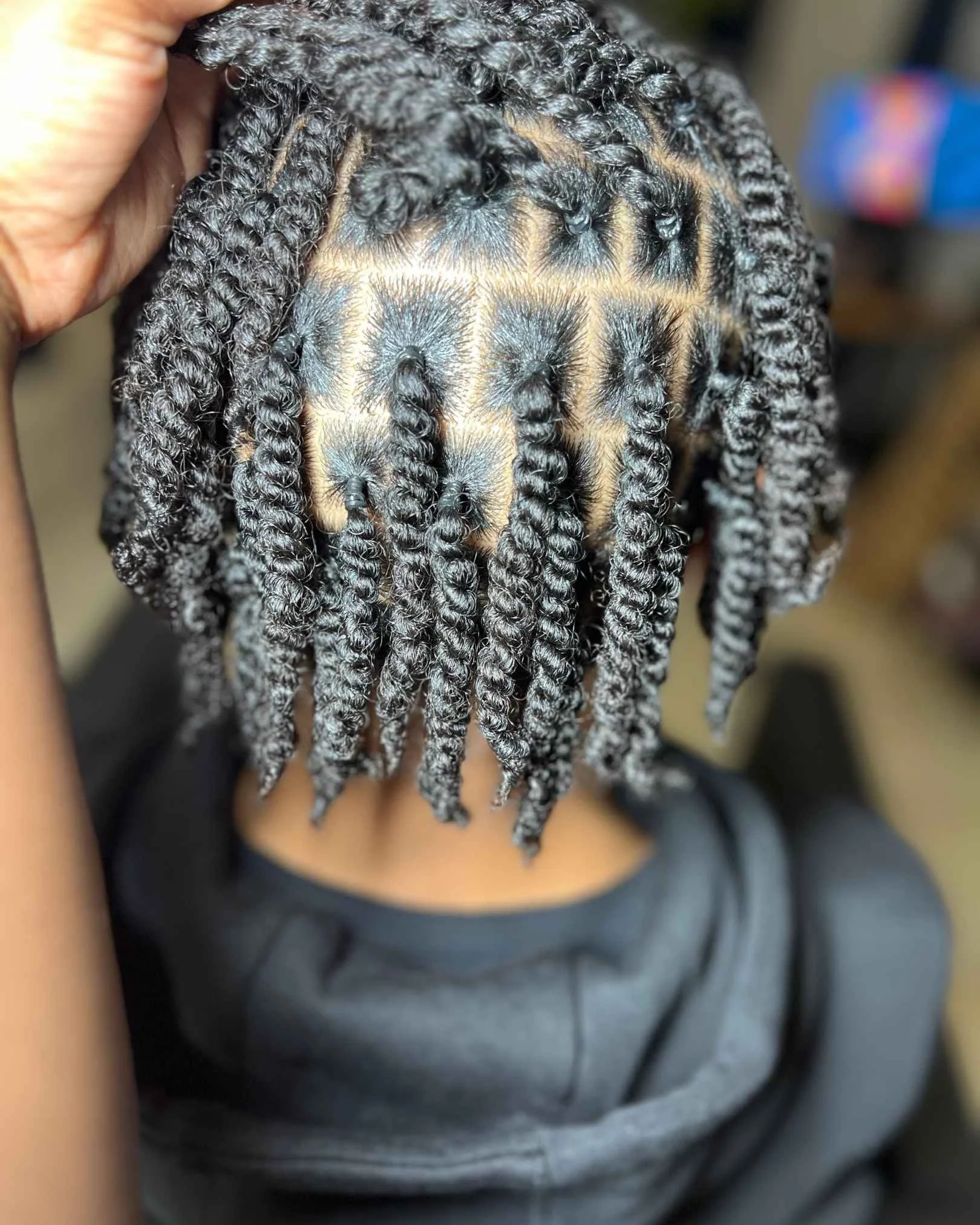 Tresses Lyon, twists braids sans meches, coiffure pour homme sans extensions. sur la photo on voit un jeune homme africain qui porte des tresse avec des élastiques noir  pour prendre soins de ses cheveux et sublimer son afro capillaires