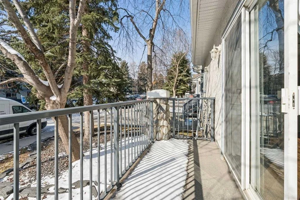 View from a balcony or patio with a metal railing, outside trees with snow, and neighboring houses in the background.