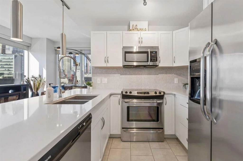Modern kitchen with white cabinets, stainless steel appliances, and a large island with a double sink.