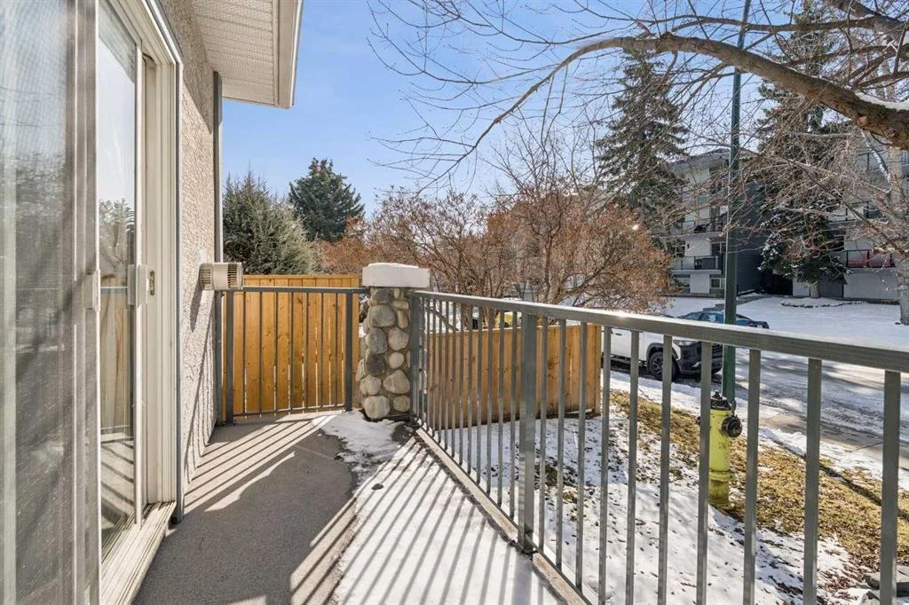 Balcony with snow-covered ground, trees, and a neighboring building in the background.