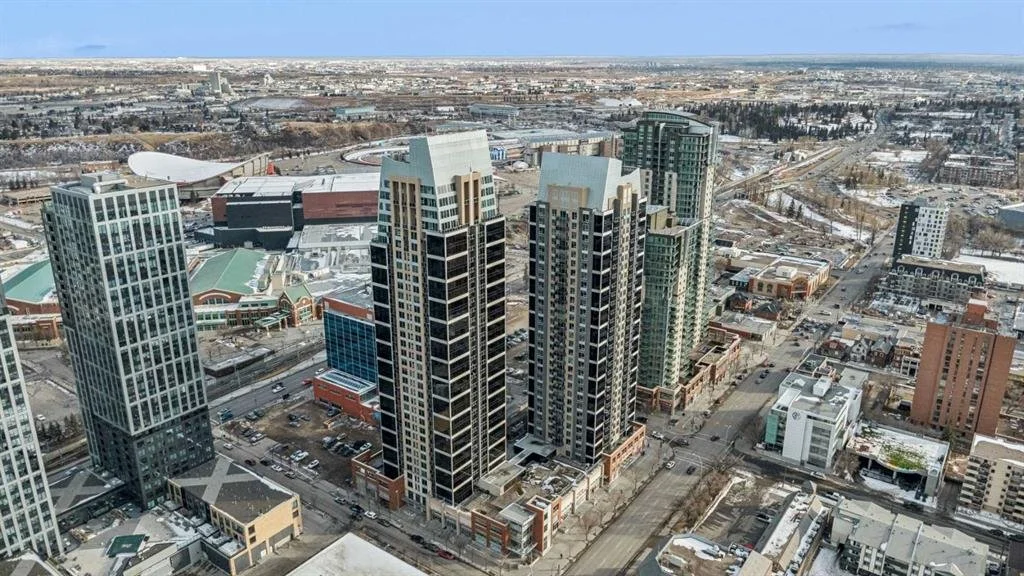 Aerial view of a city skyline with tall modern skyscrapers and buildings, some snow-covered, with roads and streets below during winter.