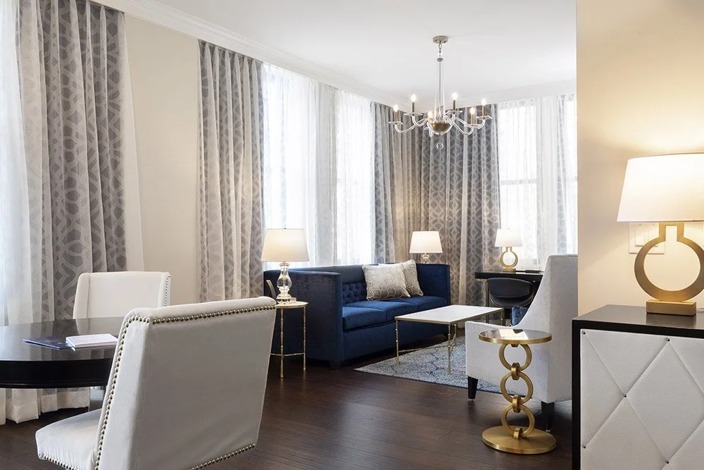 Suite living room with a sofa, chandelier and tall windows