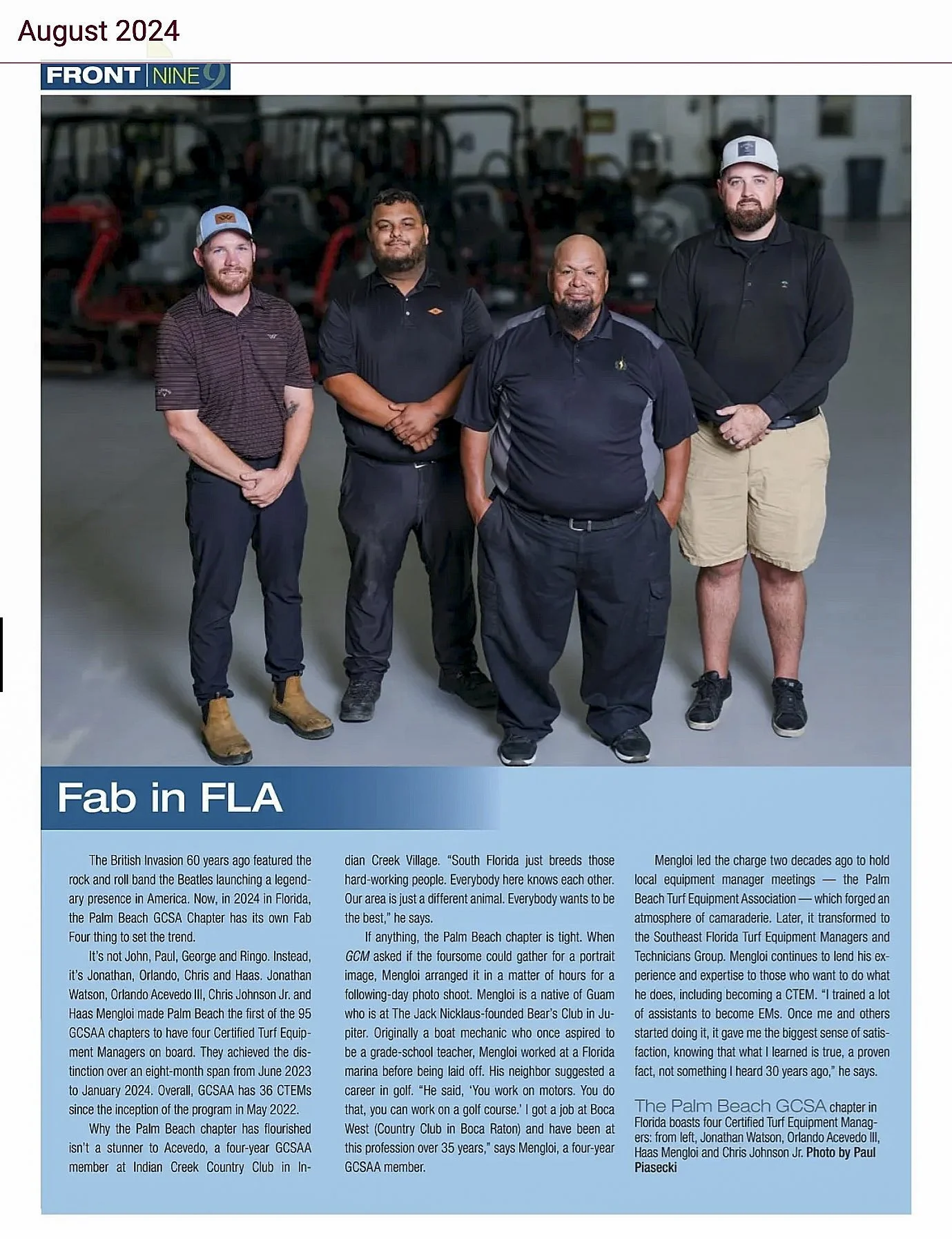 Group of four men standing in an indoor space with equipment in the background, posing for a photo.