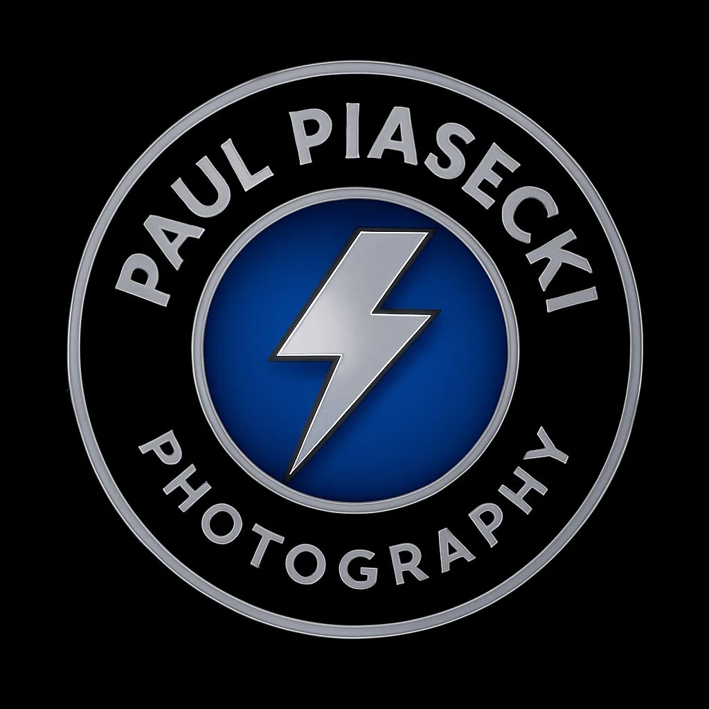 Photograph of a logo with a lightning bolt in the center, the outer circle reads 'PAUL PIASECKI PHOTOGRAPHY' in silver lettering on a black background.